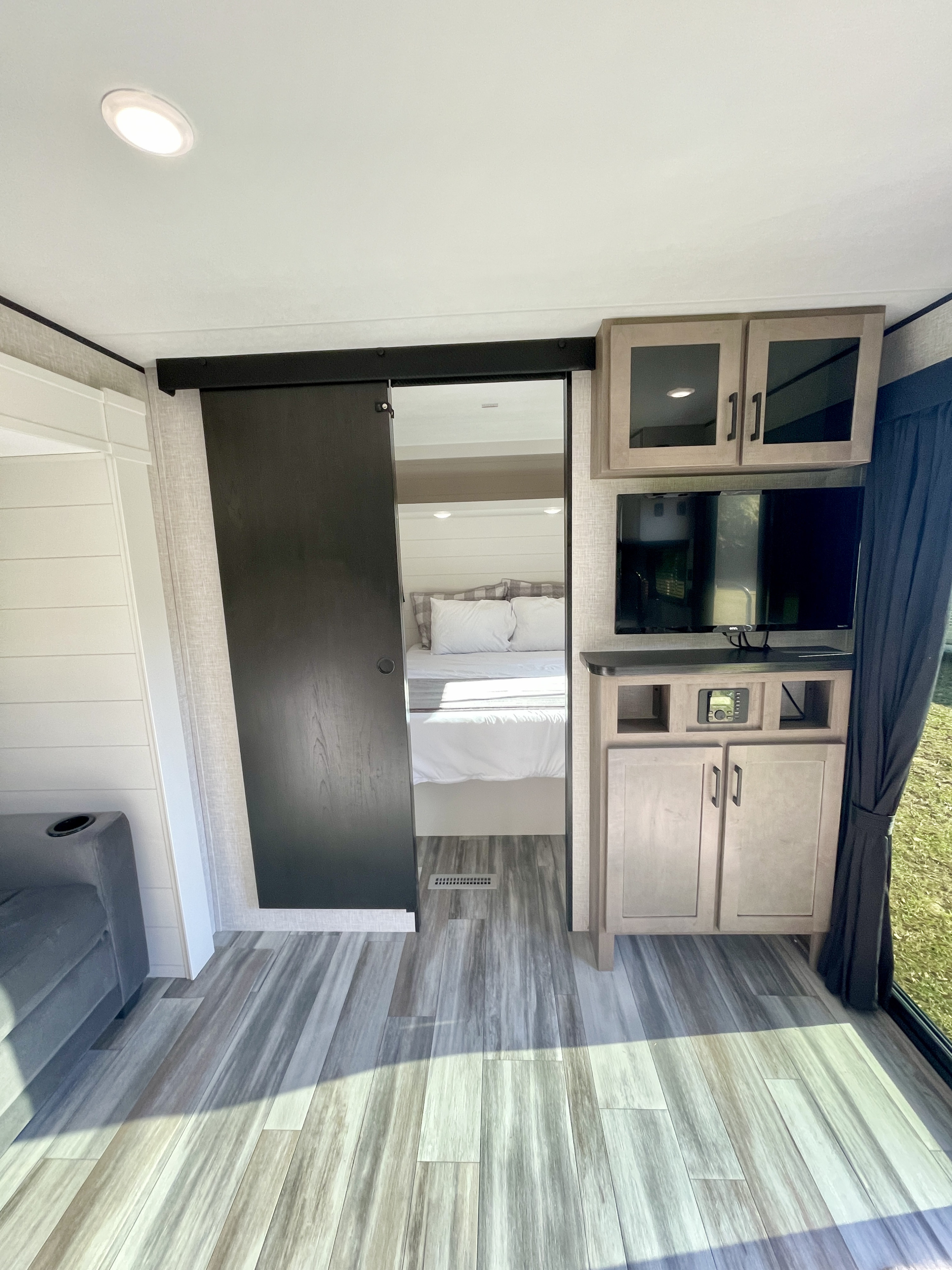 Spacious RV rental interior featuring a living area with entertainment center, TV, and modern barn door leading to the comfy bedroom.. Jayco Jay Flight 380DQS 2025