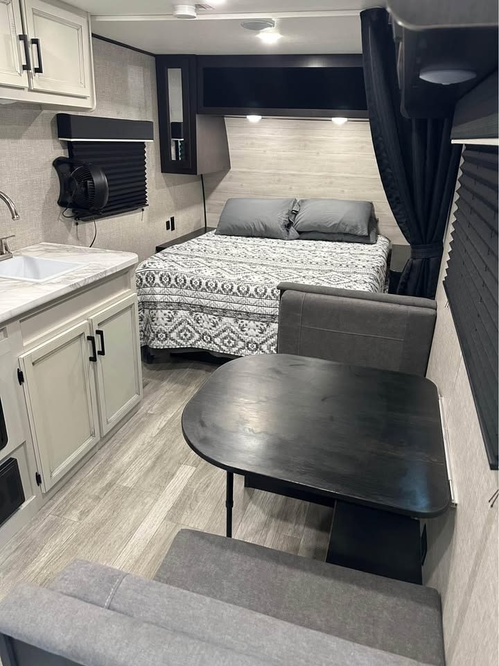 RV rental interior with a light kitchen, comfortable bed, and dining nook, showcasing efficient compact living.. Jayco Jay Flight SLX 2023