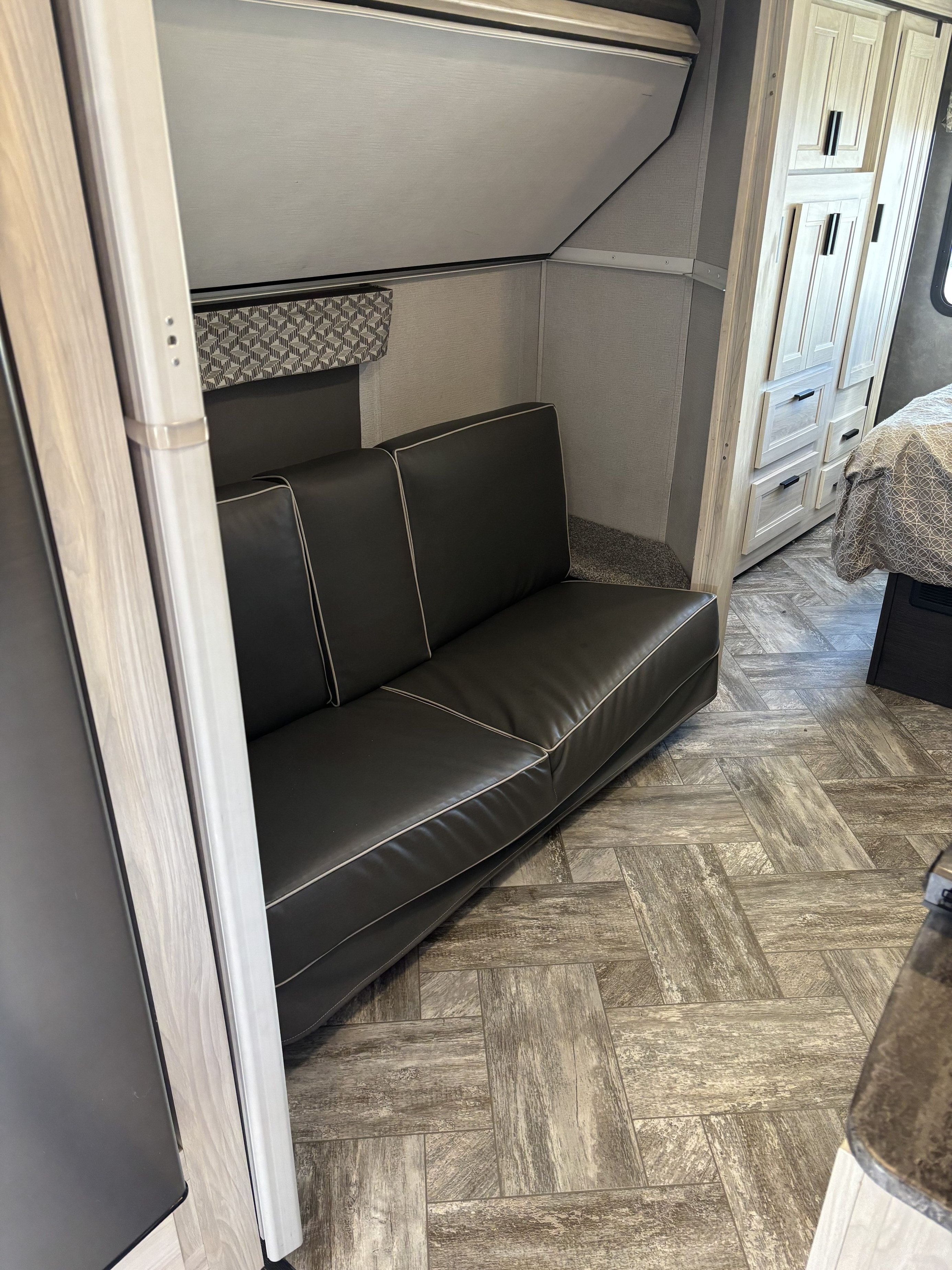 Discover this RV rental's modern interior: black sofa, overhead bunk, light wood cabinets, and textured herringbone floor.. Forest River Forester- Model 3251DS-LE 2022
