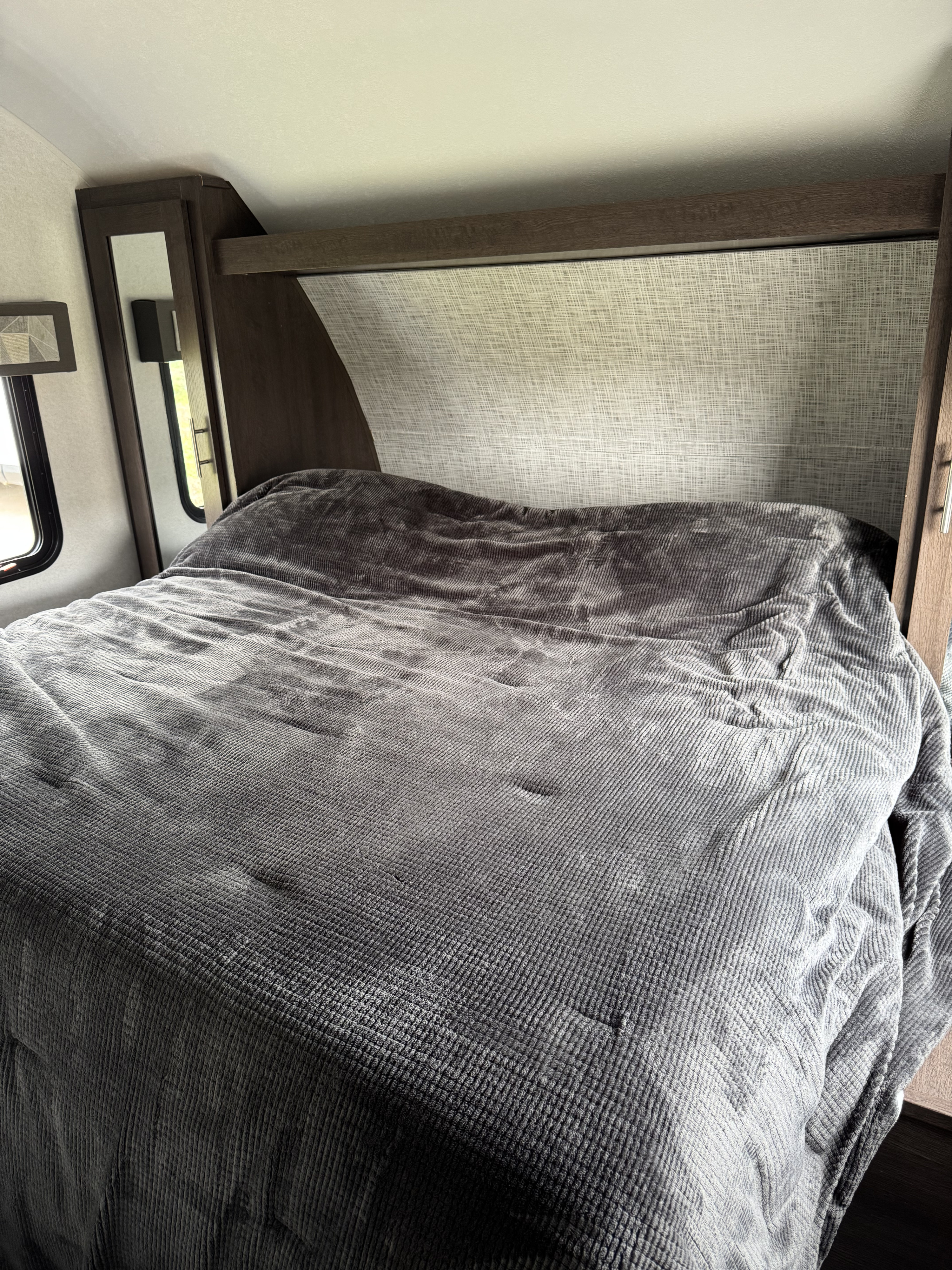 This cozy RV rental bedroom offers a comfortable gray bed, built-in storage, and bright windows for your travels.. Forest River Salem FSX 2019