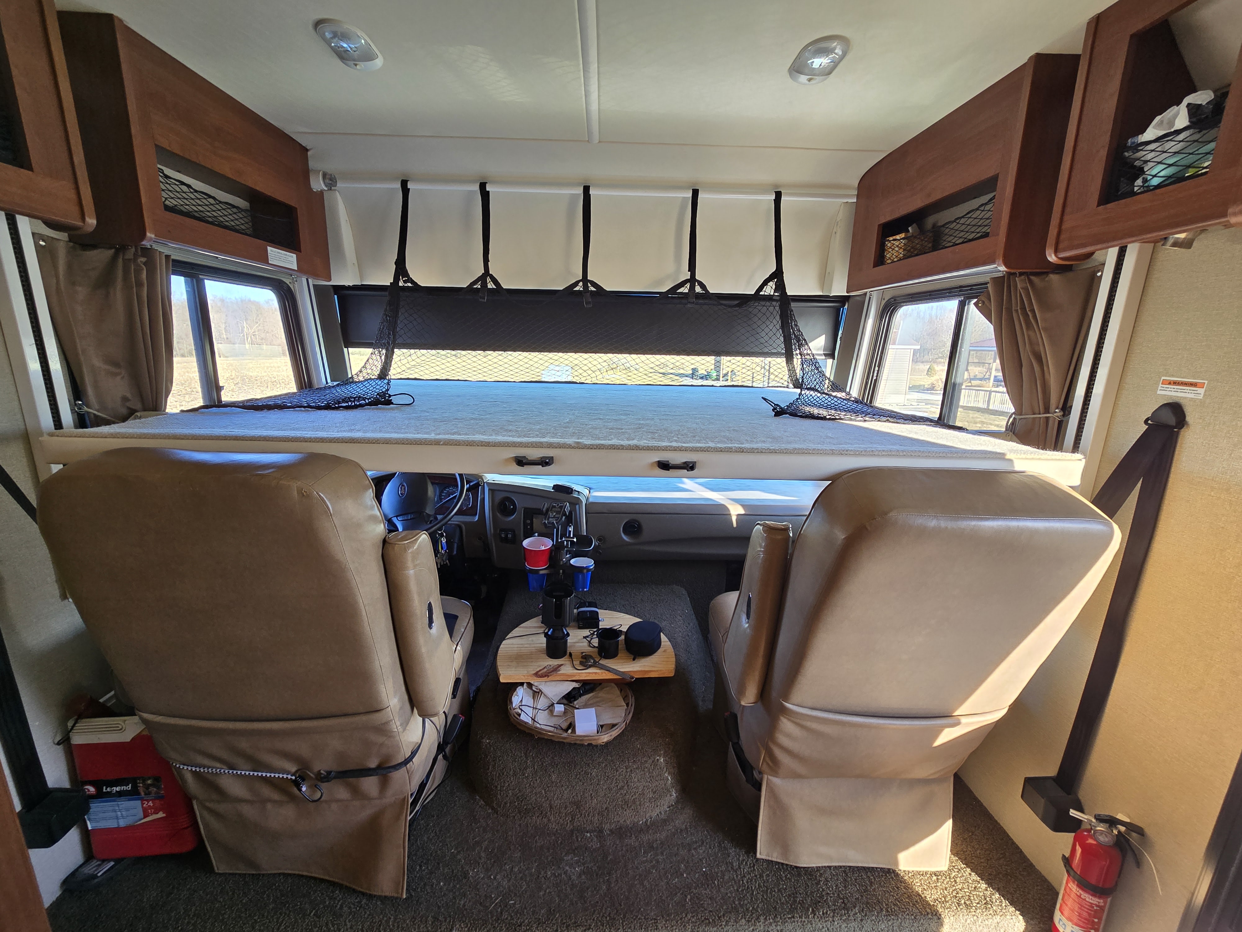 Spacious RV rental interior: cockpit, leather captain's chairs, overhead bunk bed, and ample storage.. Fleetwood Storm 35SK 2016