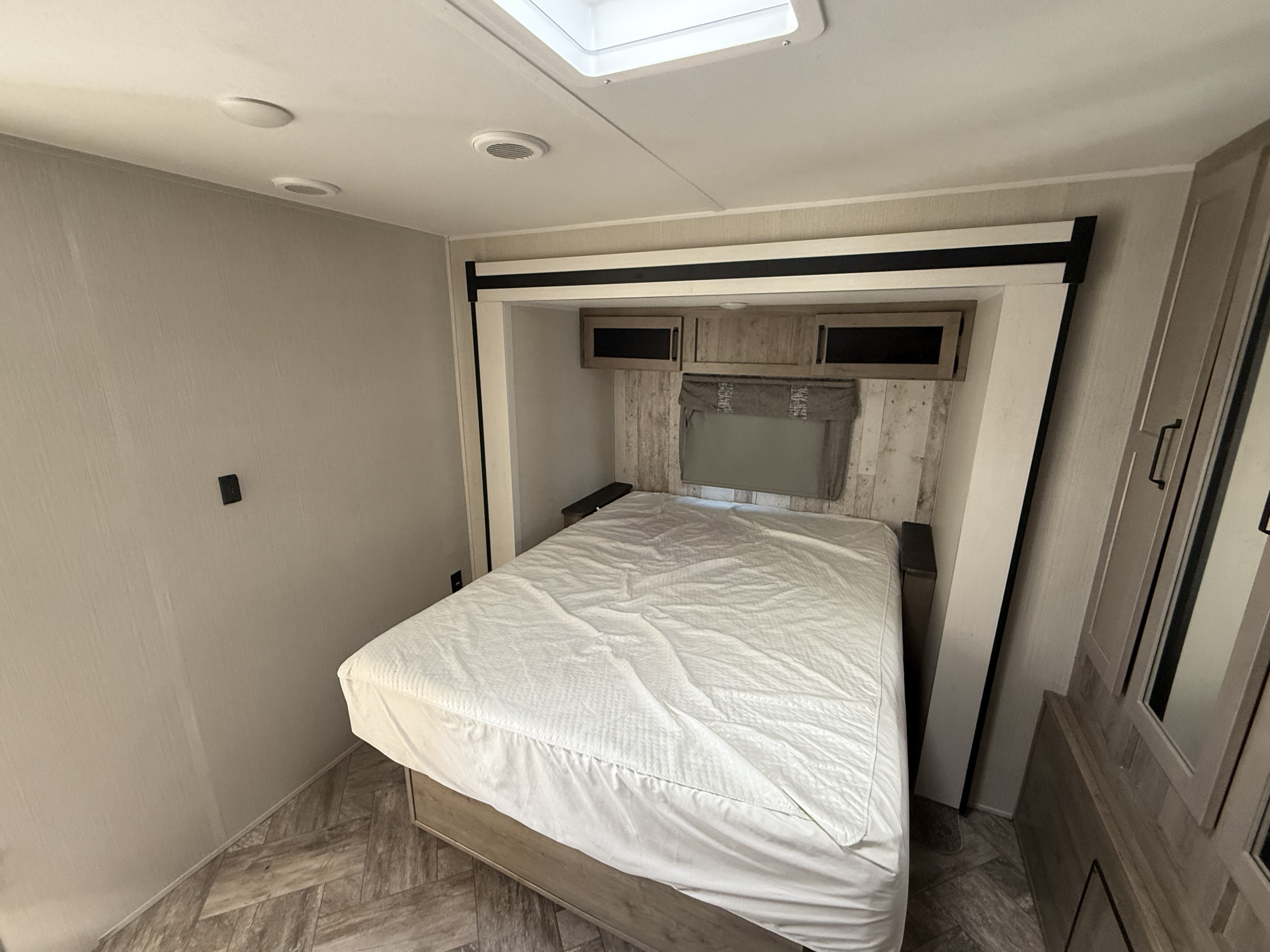 RV rental bedroom with a neatly made bed, overhead storage, and light-colored interior, perfect for travel comfort.. Palomino Puma 2023