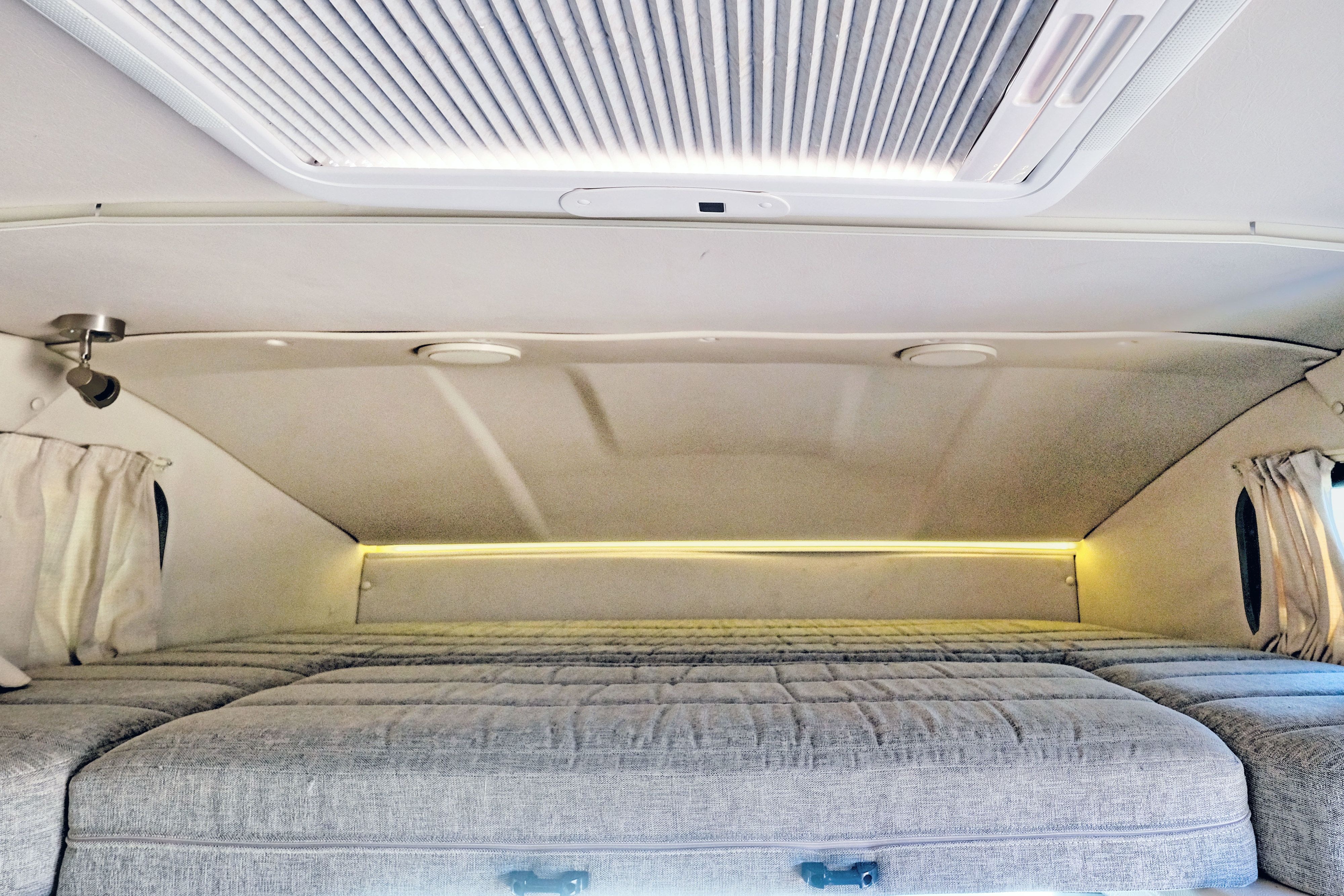 Cozy RV rental interior shows a spacious bed with ambient lighting, a skylight, and curtains.. Winnebago View 2016