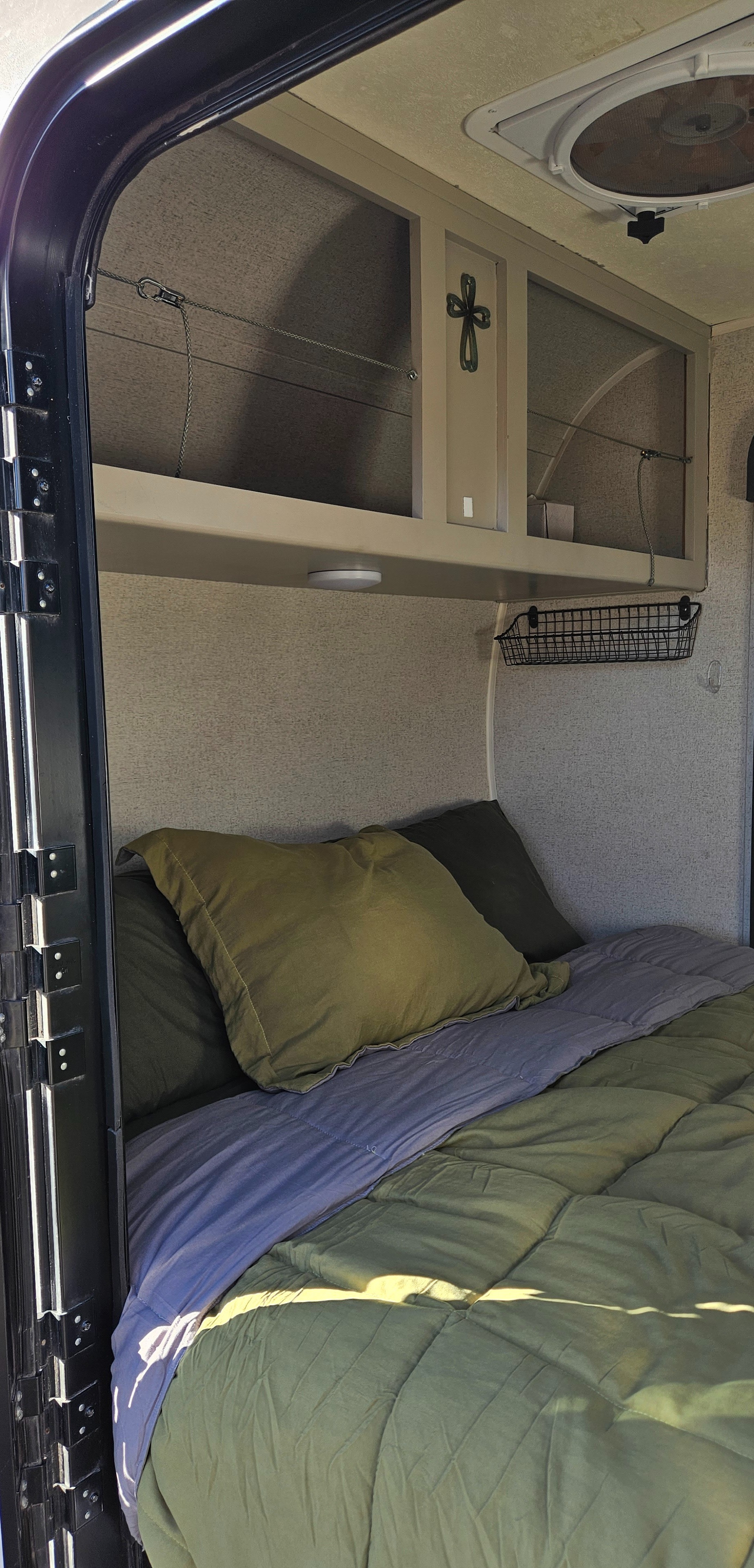 Cozy RV rental bedroom with olive green bed, purple blanket, overhead cabinets, and ceiling fan for comfortable mobile living.. Forest River GeoPro 12RK 2017