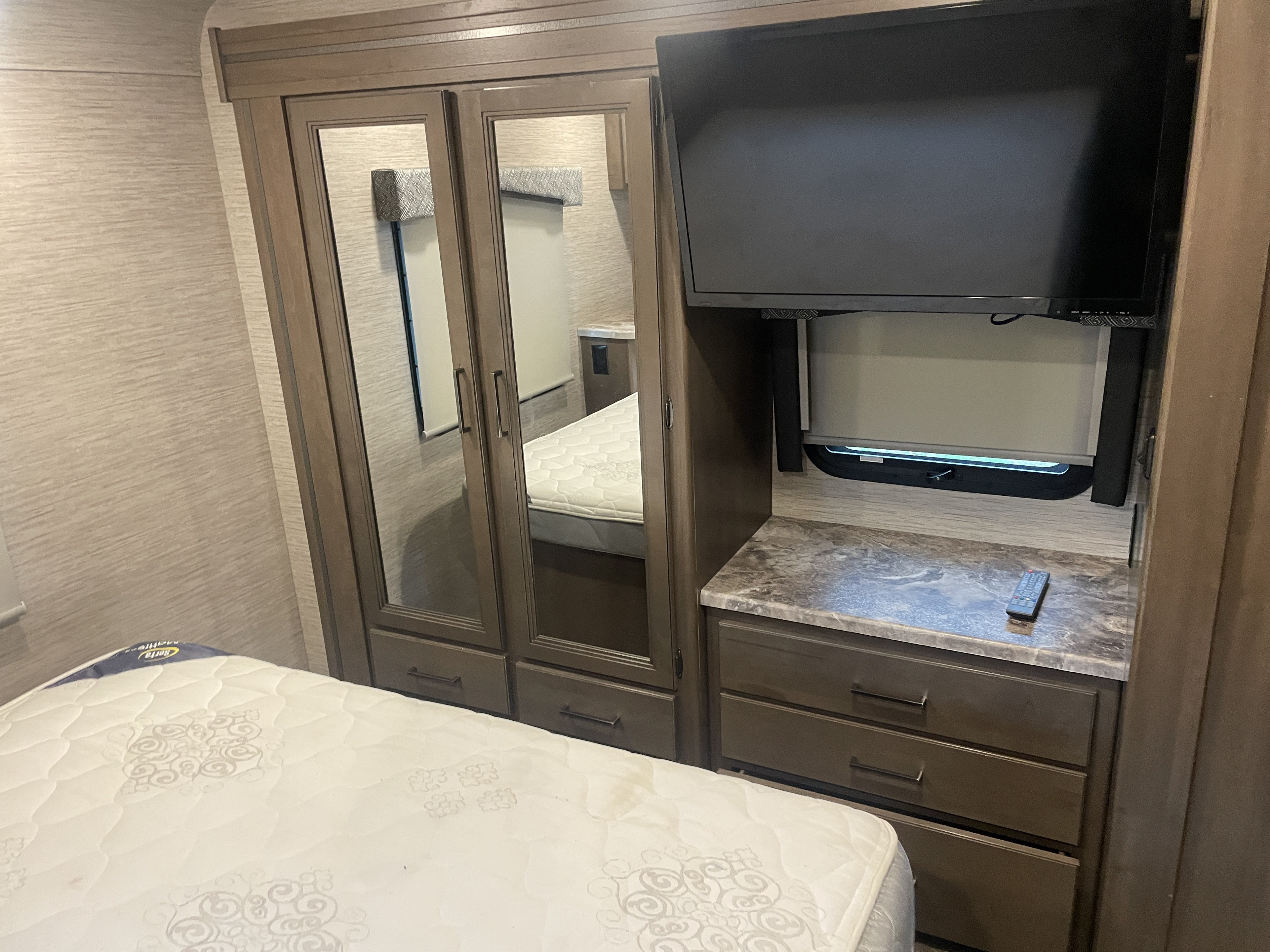 RV rental bedroom: Features a mirrored closet, mounted TV, dresser drawers, and a comfortable bed.. Thor Chateau 2022