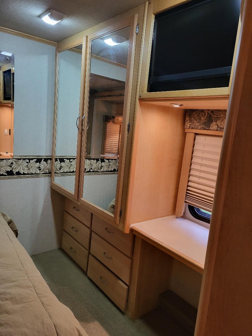 RV rental bedroom: Built-in wooden dresser with mirrored cabinet, desk, and TV maximize comfort for your journey.. Southwind Southwind Motorhome 2005