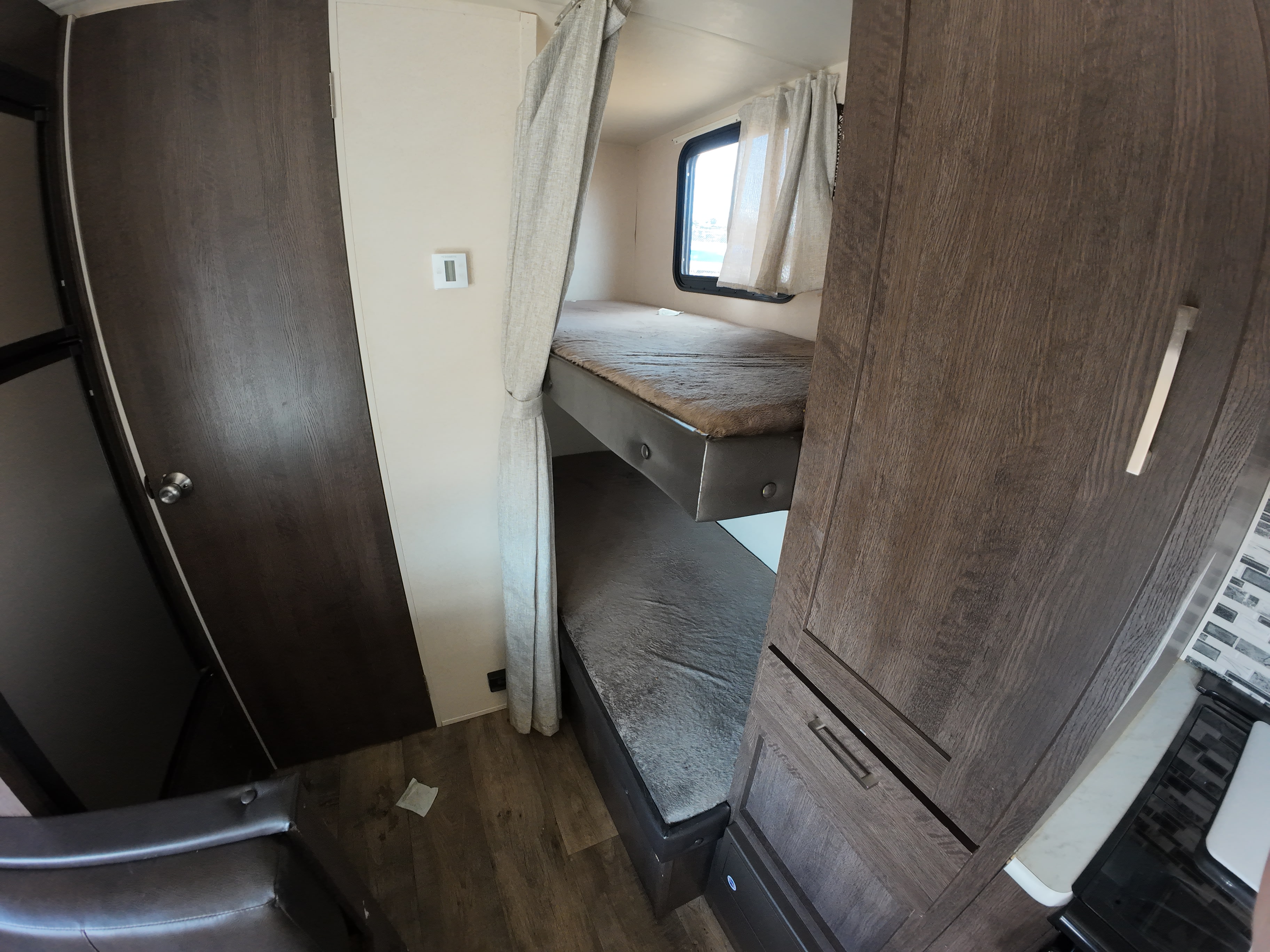 Compact RV rental interior showcasing cozy bunk beds, a storage cabinet, and a door, ideal for family trips.. Forest River Salem Cruise Lite 2018