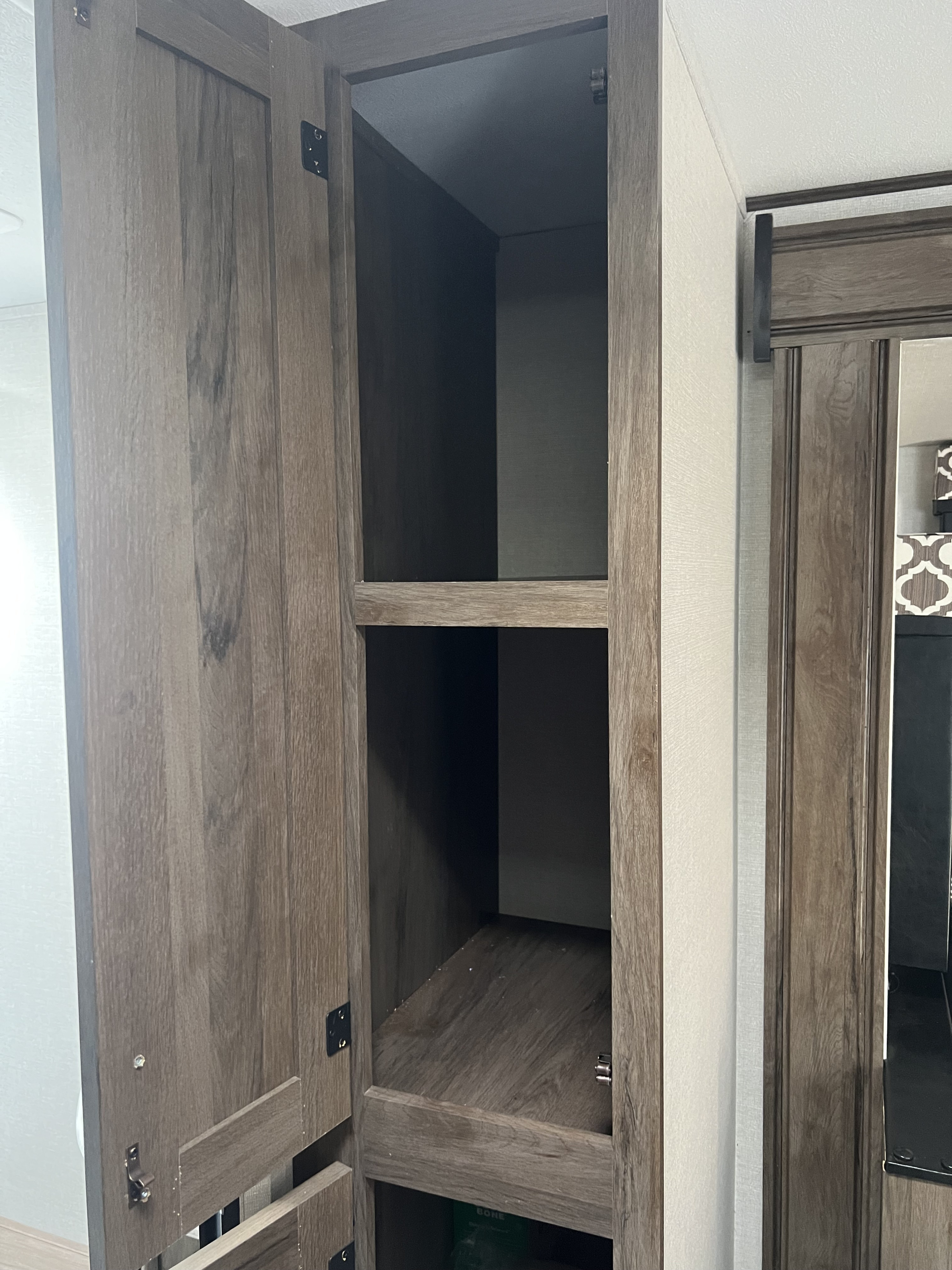 RV rental: Open wood-grain storage cabinet with multiple shelves, typical of a compact RV interior.. Forest River Tracer 2020