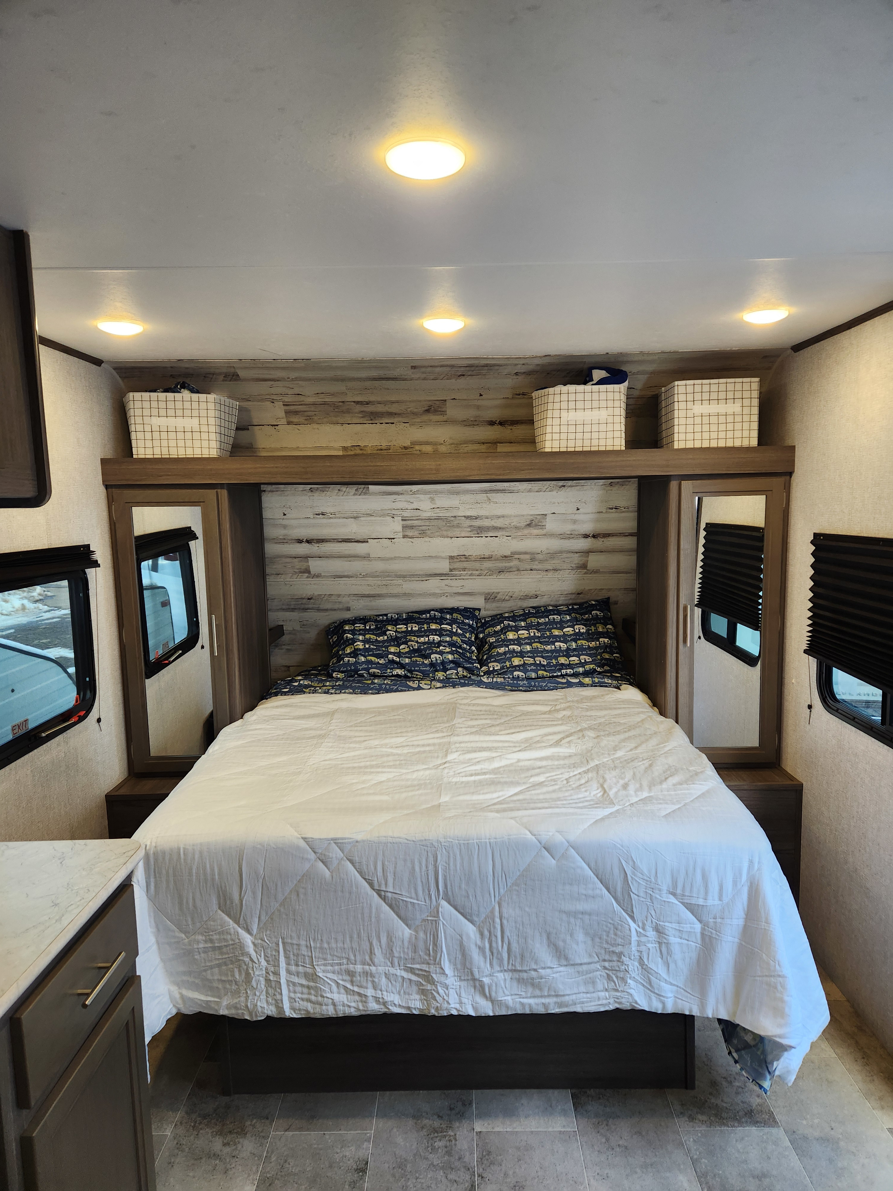 Spacious RV rental bedroom featuring a queen bed, overhead storage, and dual windows.. Dutchmen Kodiak SE 2021