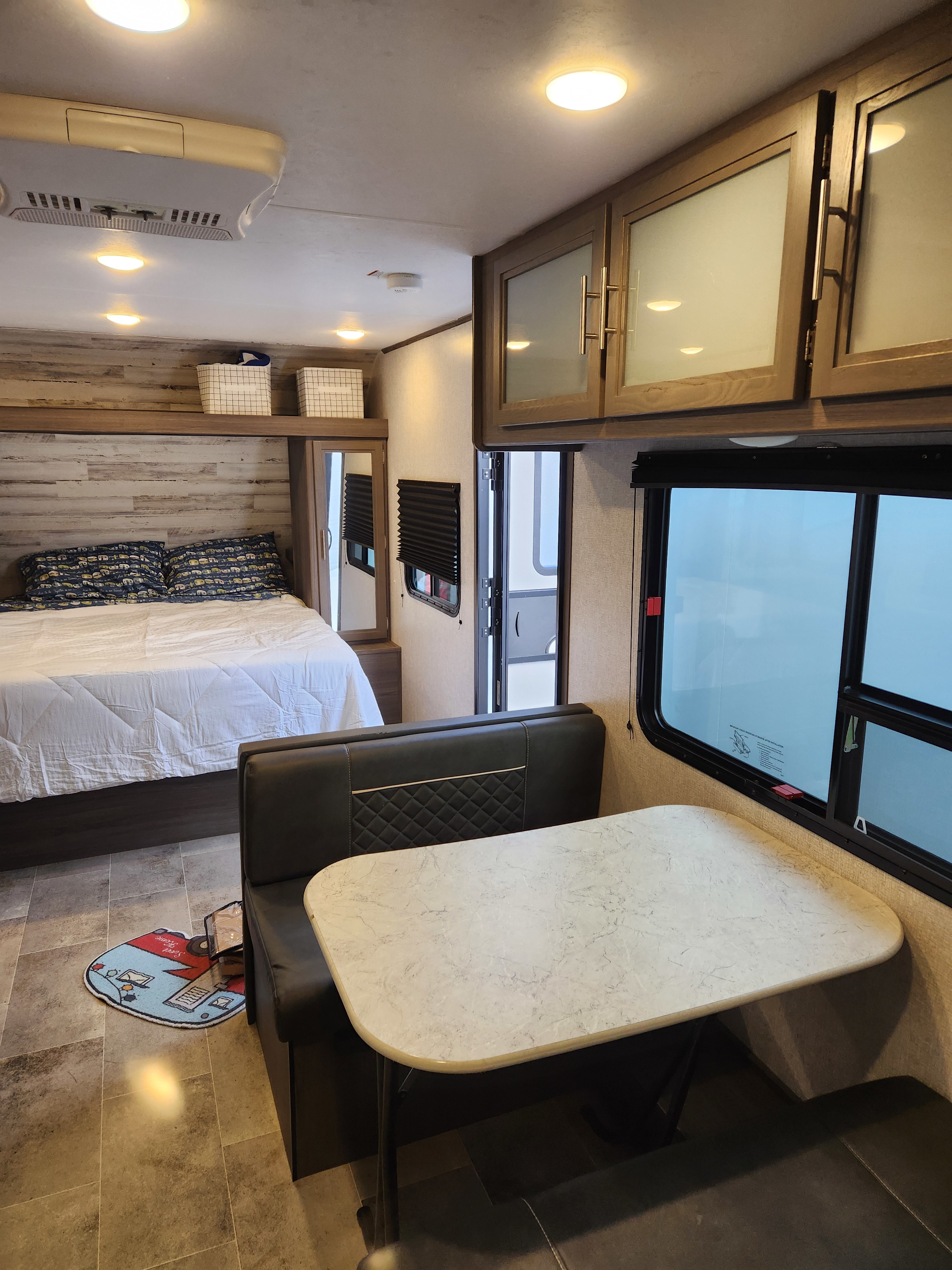 Bright RV rental interior showing a bed, dinette, and overhead storage. Enjoy compact living on the road.. Dutchmen Kodiak SE 2021