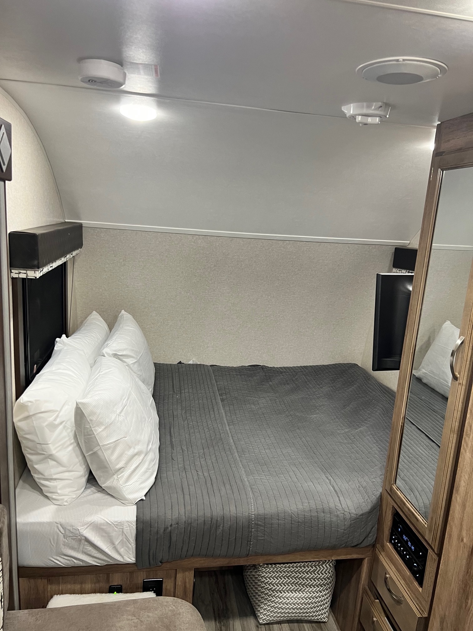 Compact RV rental bedroom featuring a cozy bed, overhead lighting, and built-in storage.. Jayco Hummingbird 2019