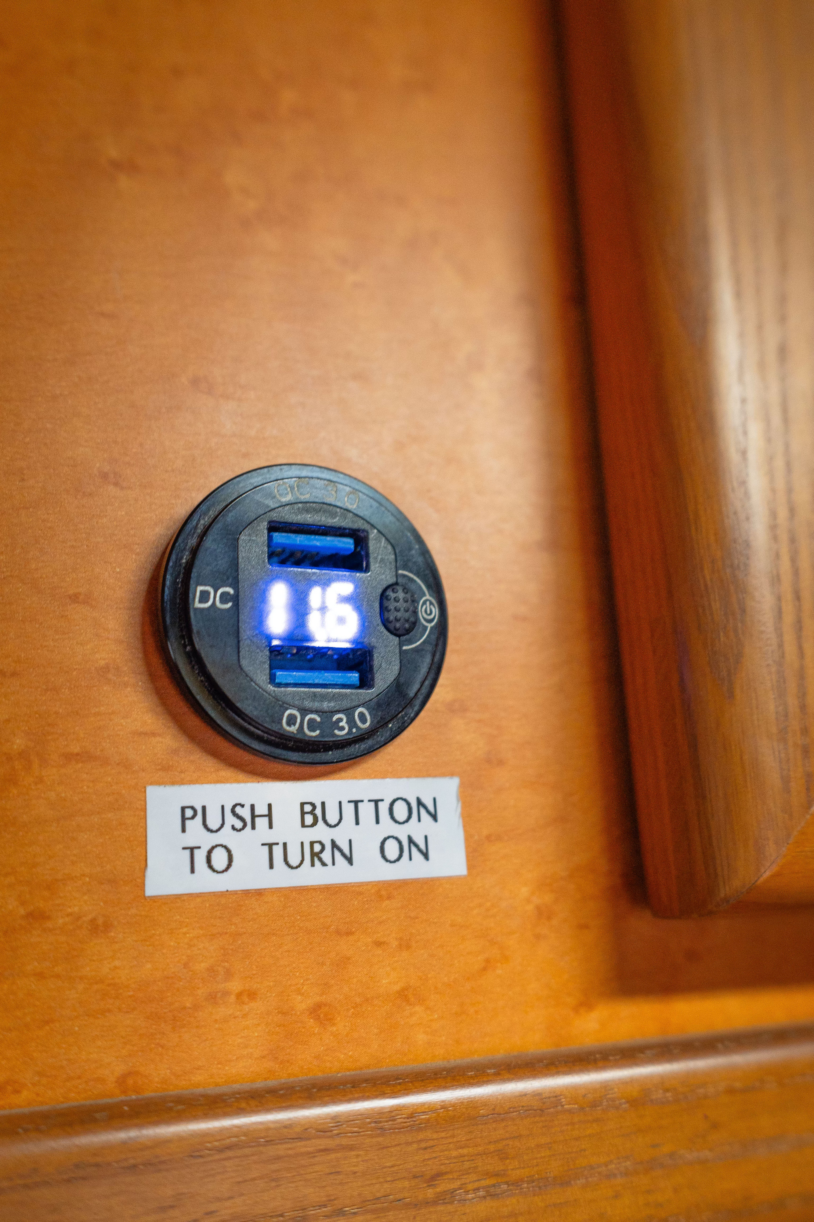 RV rental interior: A USB charger with a blue digital display showing '1 16', and a 'PUSH BUTTON TO TURN ON' label.. Toyota Hiace 2007