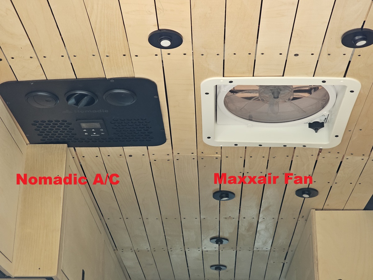 Ceiling view inside an RV rental, showing a black Nomadic A/C unit on the left and a white Maxxair Fan on the right, on light wood panels.. mercedes 144 High Roof AWD 2024