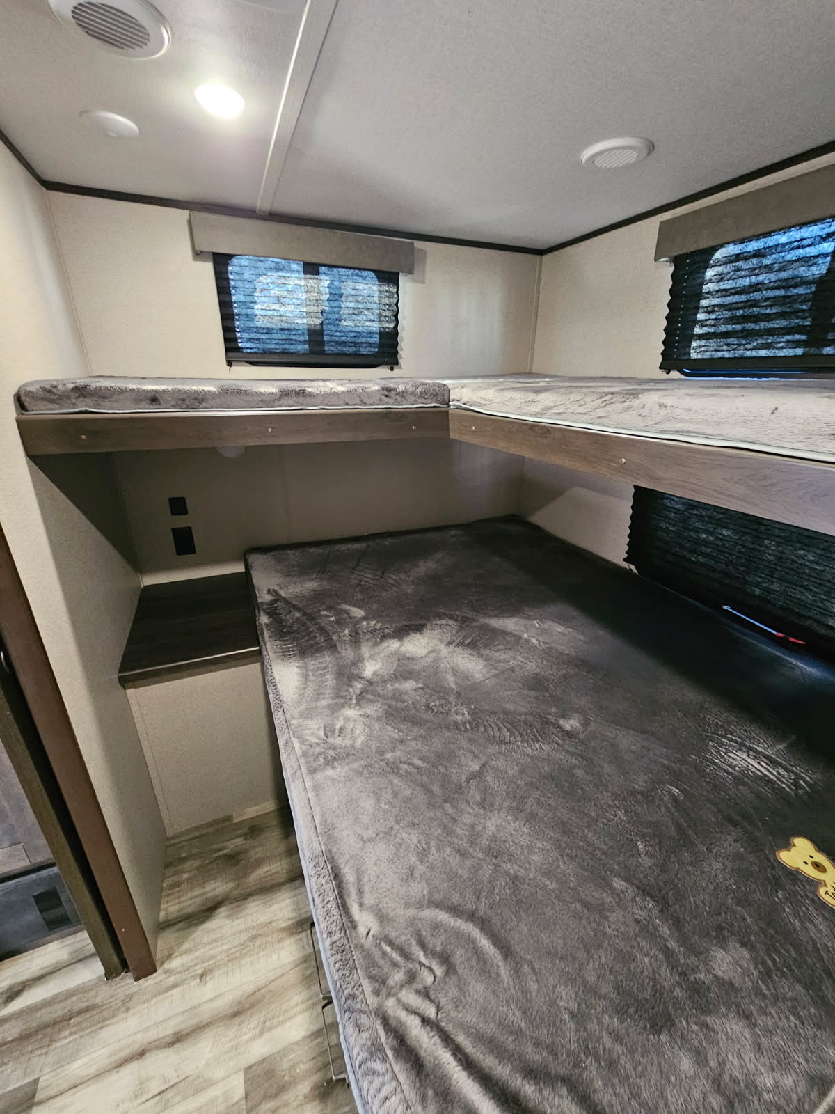RV rental bunk beds: a view of the comfortable, plush sleeping area with windows and lights in a modern camper.. Grand Design Transcend Xplor 2023