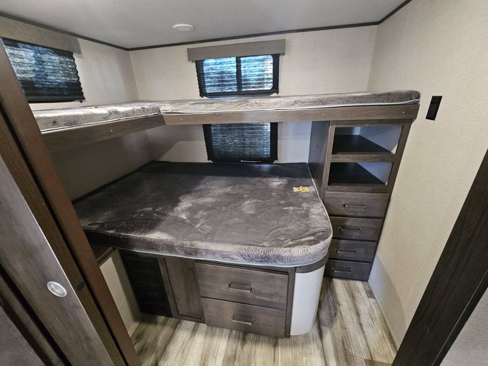 Cozy RV rental bunk room featuring L-shaped bunks, ample storage drawers, and shelves, ideal for families.. Grand Design Transcend Xplor 2023