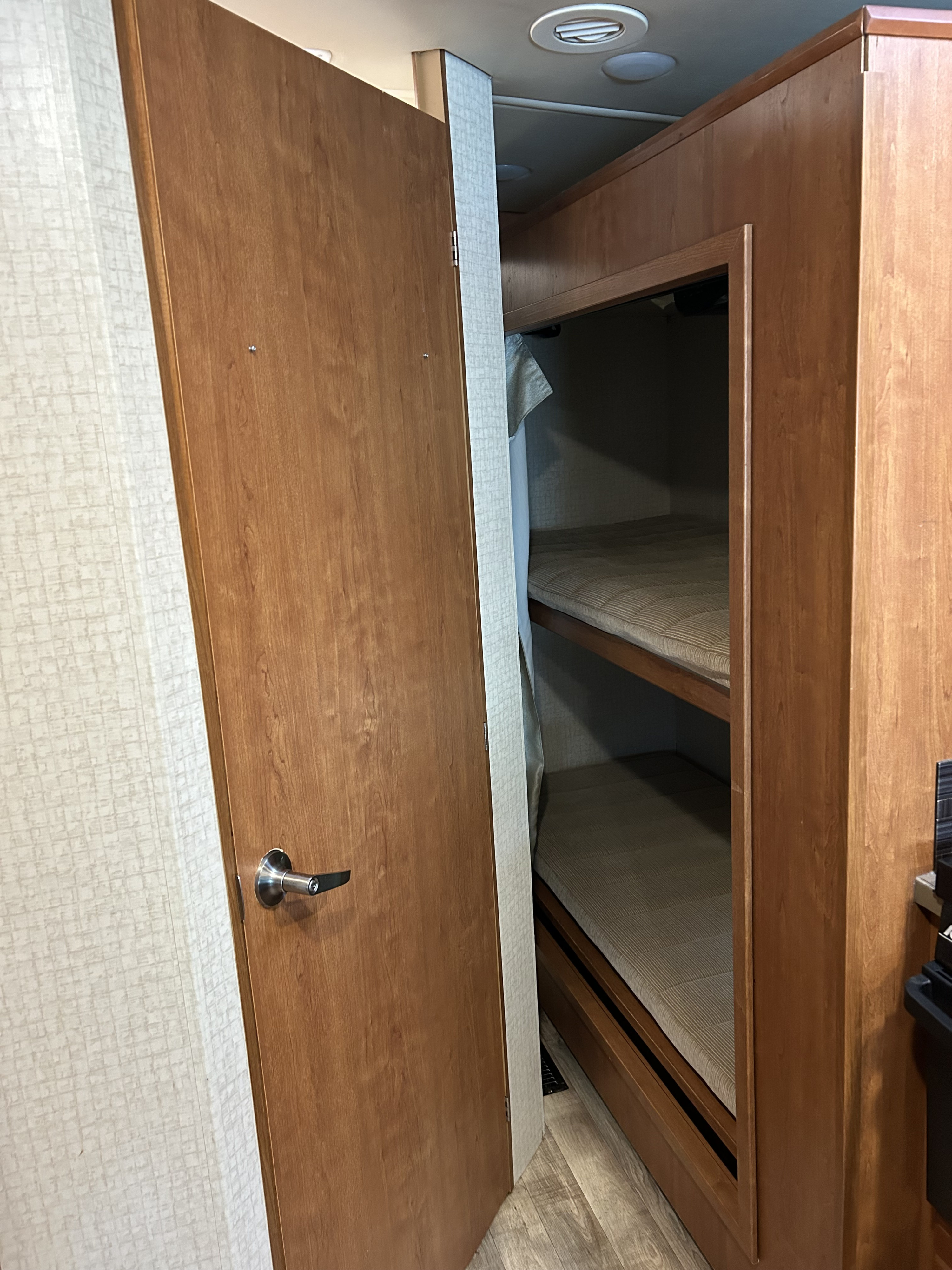 RV rental interior with an open door revealing bunk beds, ideal for compact sleeping in travel.. Winnebago Sunstar 2017