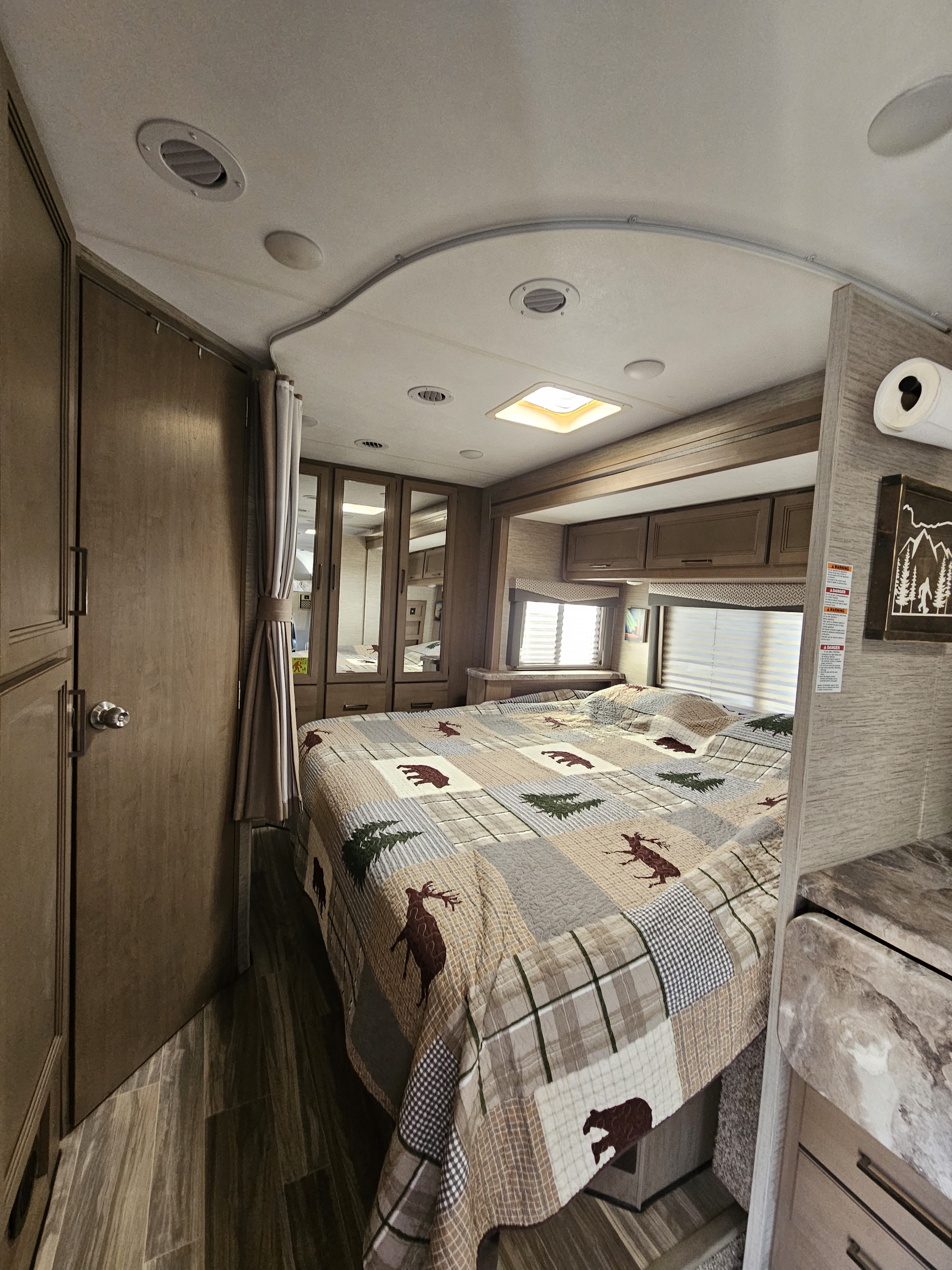 Explore this comfy RV rental bedroom, featuring a rustic quilt, ample storage, and functional design for your next road trip.. Thor Four Winds 2023