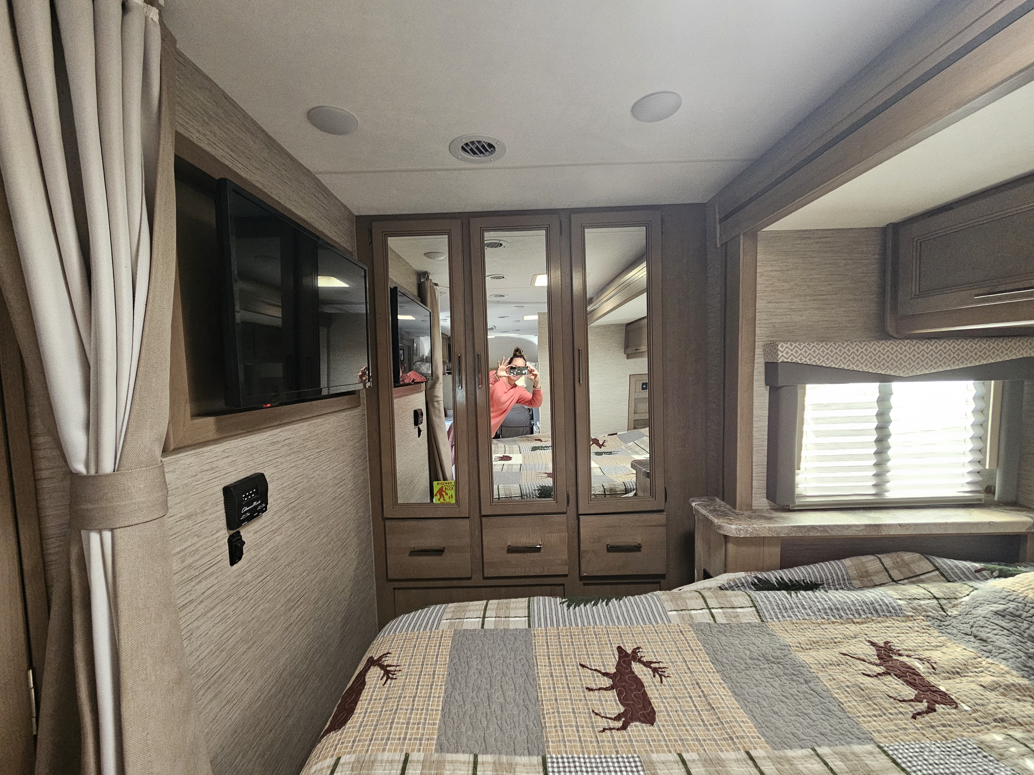Cozy RV rental bedroom with deer quilt, TV, and mirrored closet doors. Ideal for a comfortable stay.. Thor Four Winds 2023