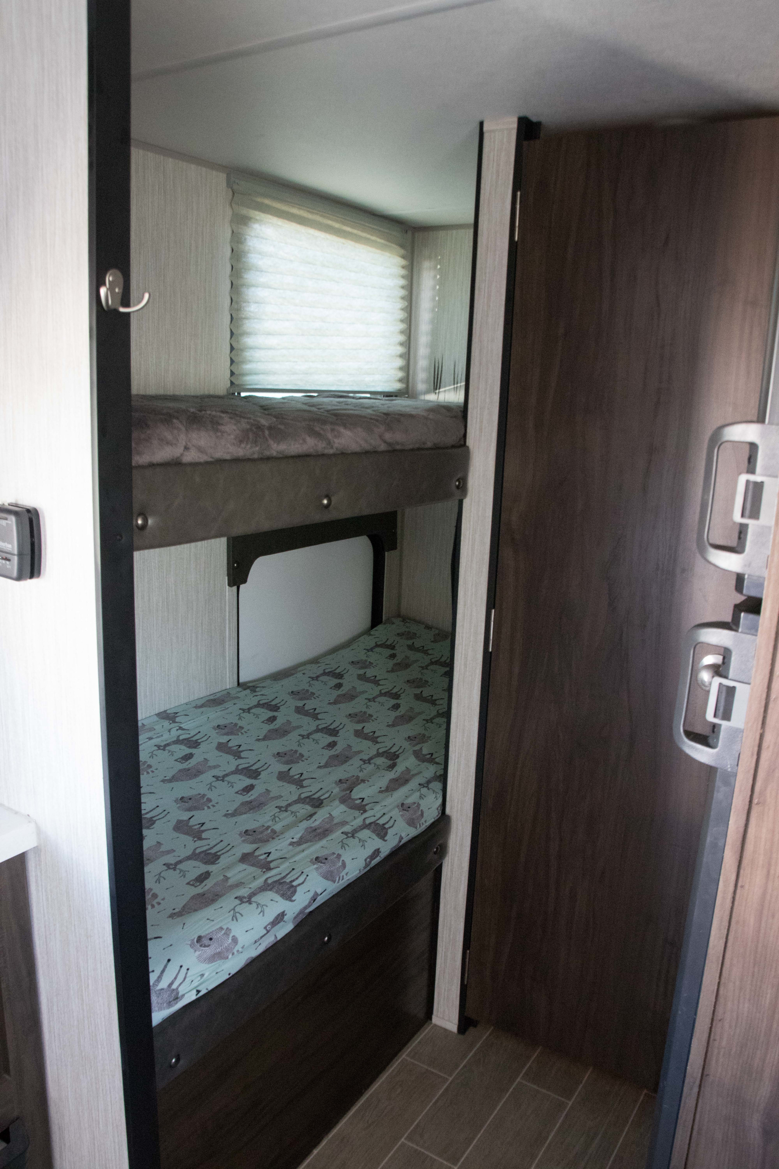 RV rental interior features bunk beds with window and controls, offering cozy sleeping space.. Forest River Cherokee Wolf Pup Black Label 2020