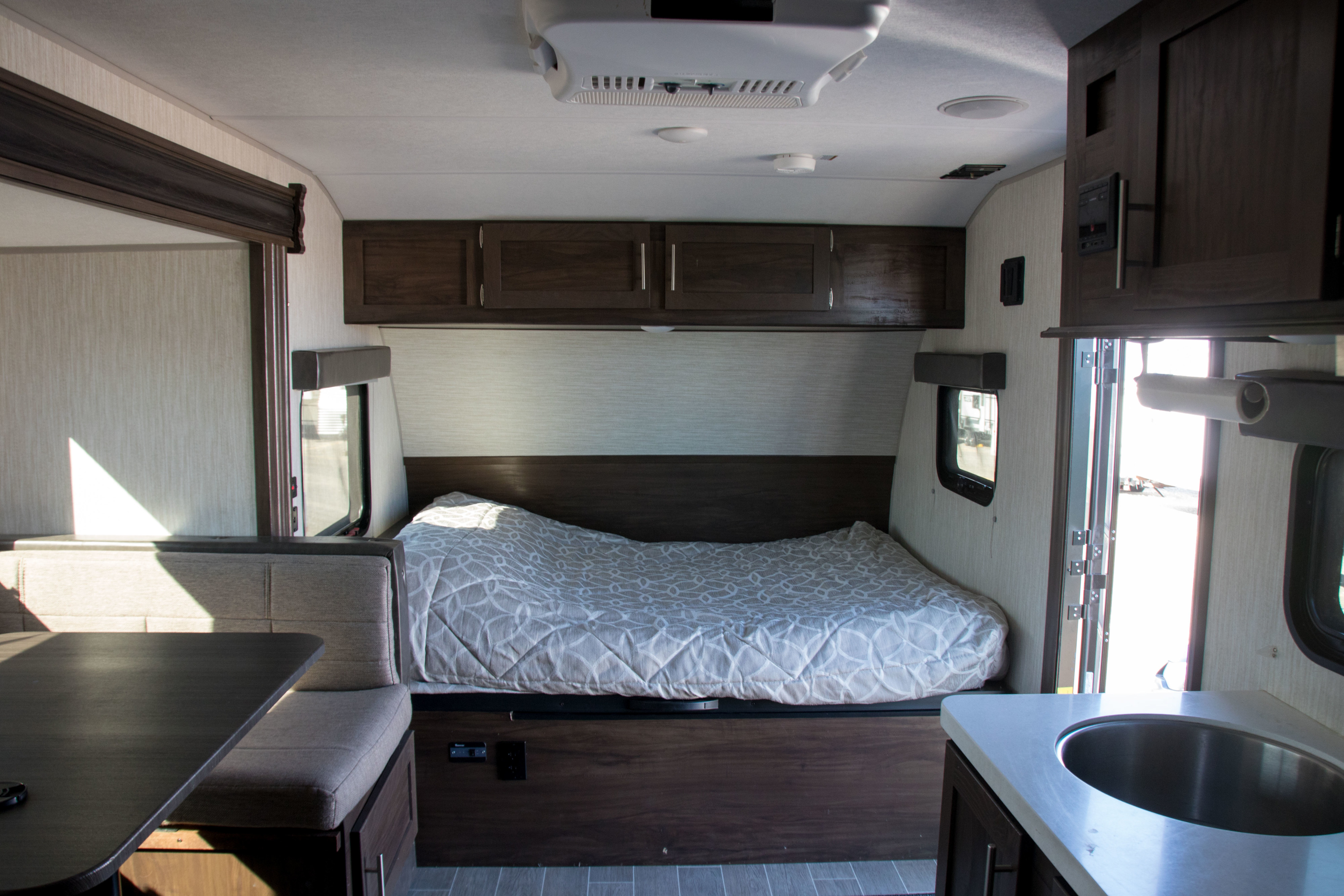 Spacious and modern RV rental interior featuring a cozy bed, dinette, and kitchen area. Perfect for your next adventure.. Forest River Cherokee Wolf Pup Black Label 2020