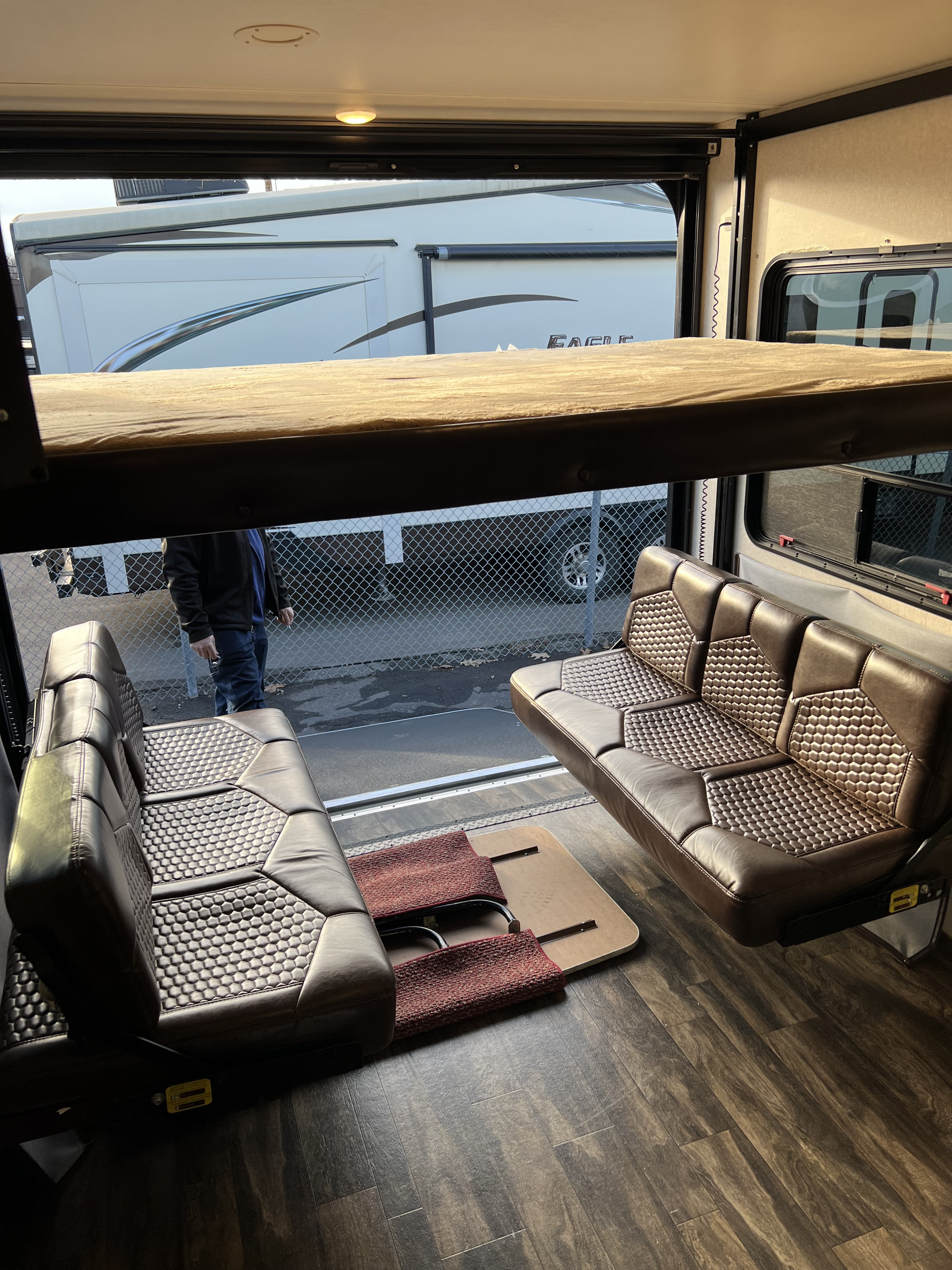 Spacious RV rental interior with comfortable brown seating, an overhead bunk, and an open rear door.. Jayco Octane 2018