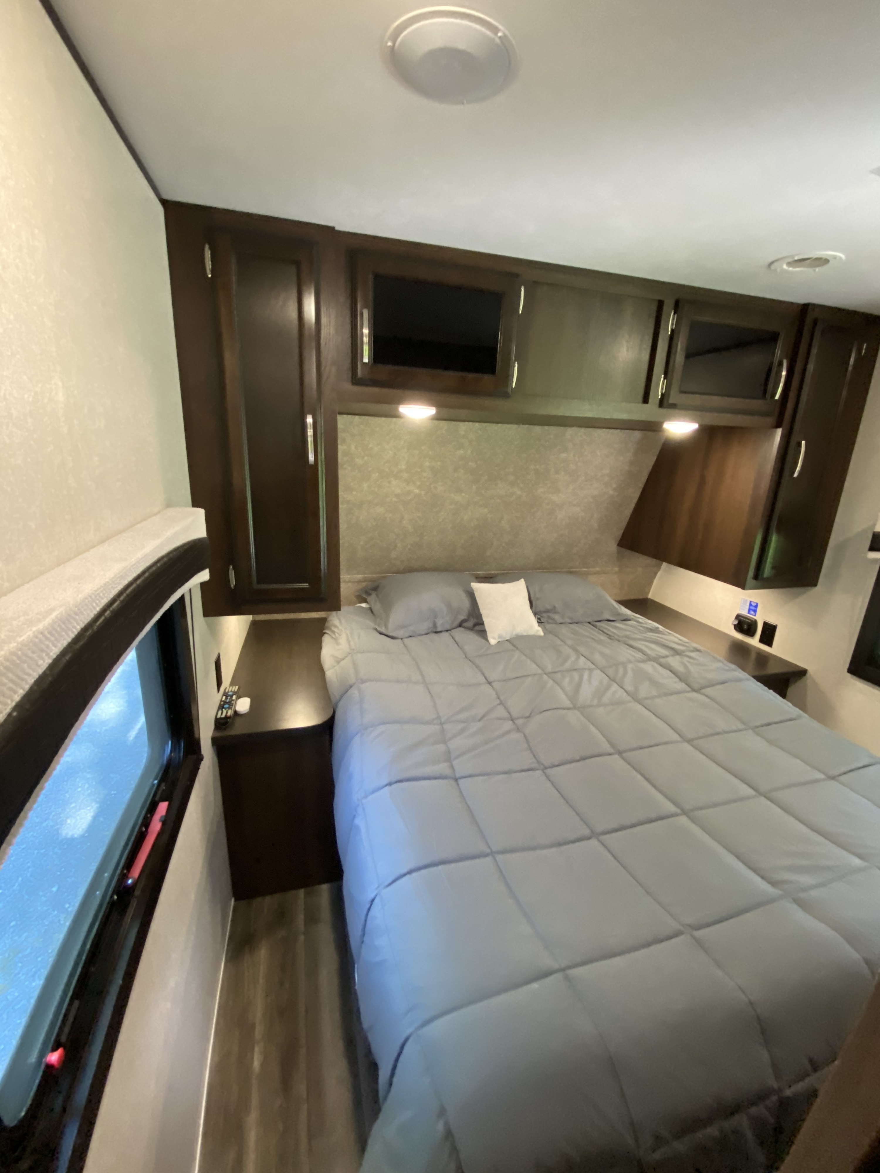 RV rental: Compact bedroom interior with a comfortable gray bed, built-in dark wood cabinets, and window.. Jayco Jay Flight 2020