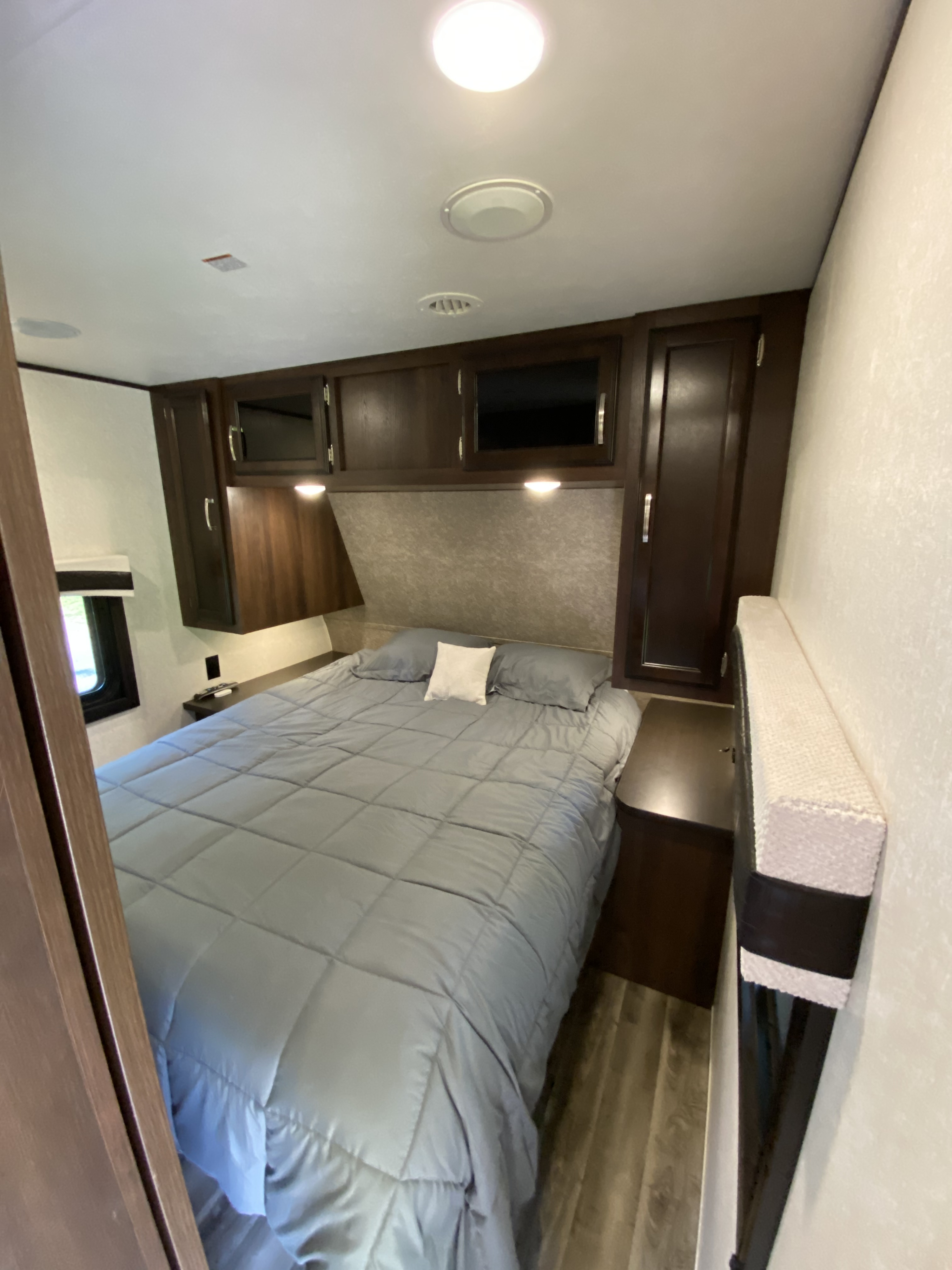 This RV rental bedroom features a comfortable bed, built-in cabinetry, and practical lighting.. Jayco Jay Flight 2020