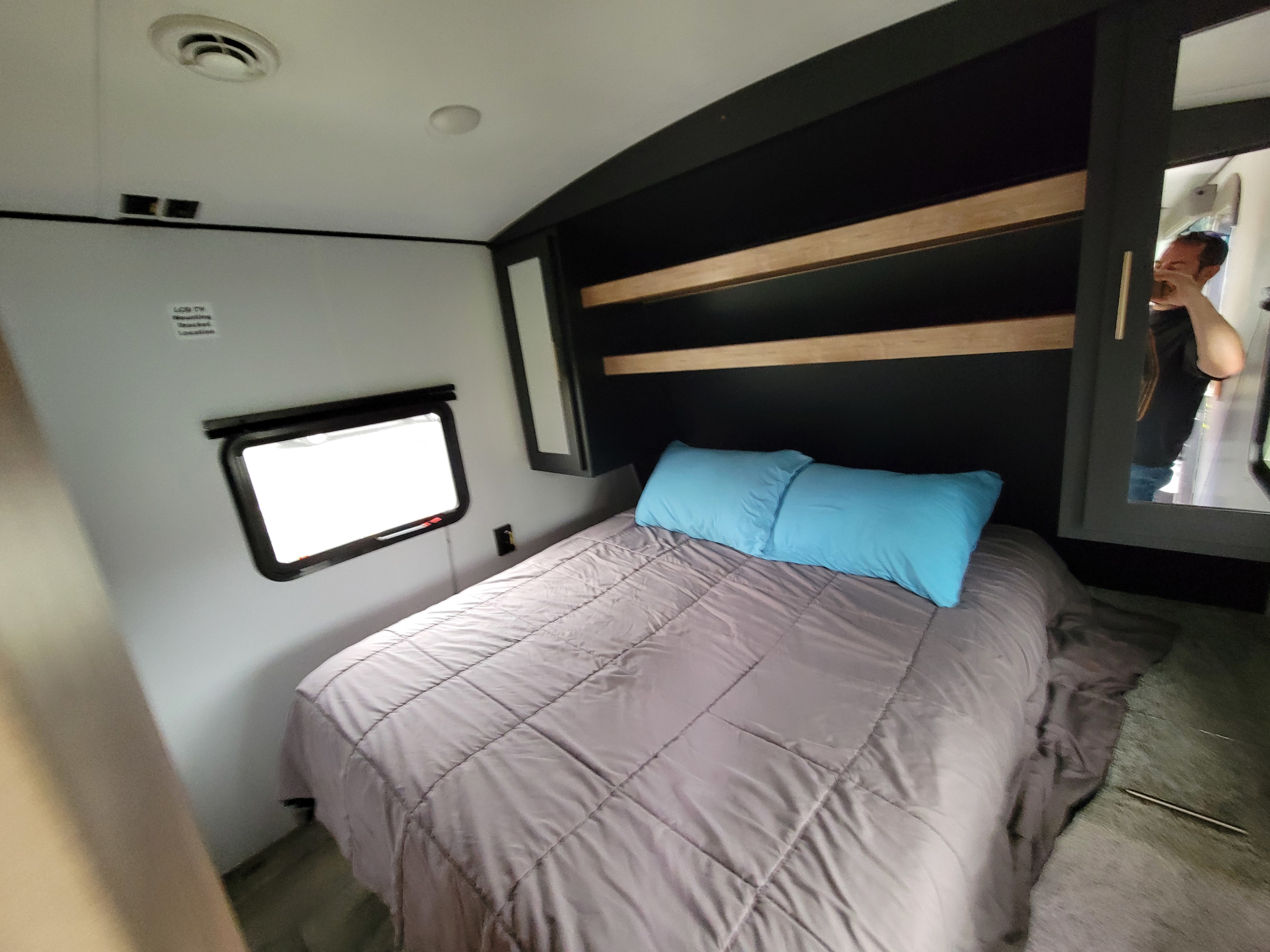 RV rental bedroom featuring a large bed, built-in shelving, window, and TV mount location.. Springdale 260TBWE 2022