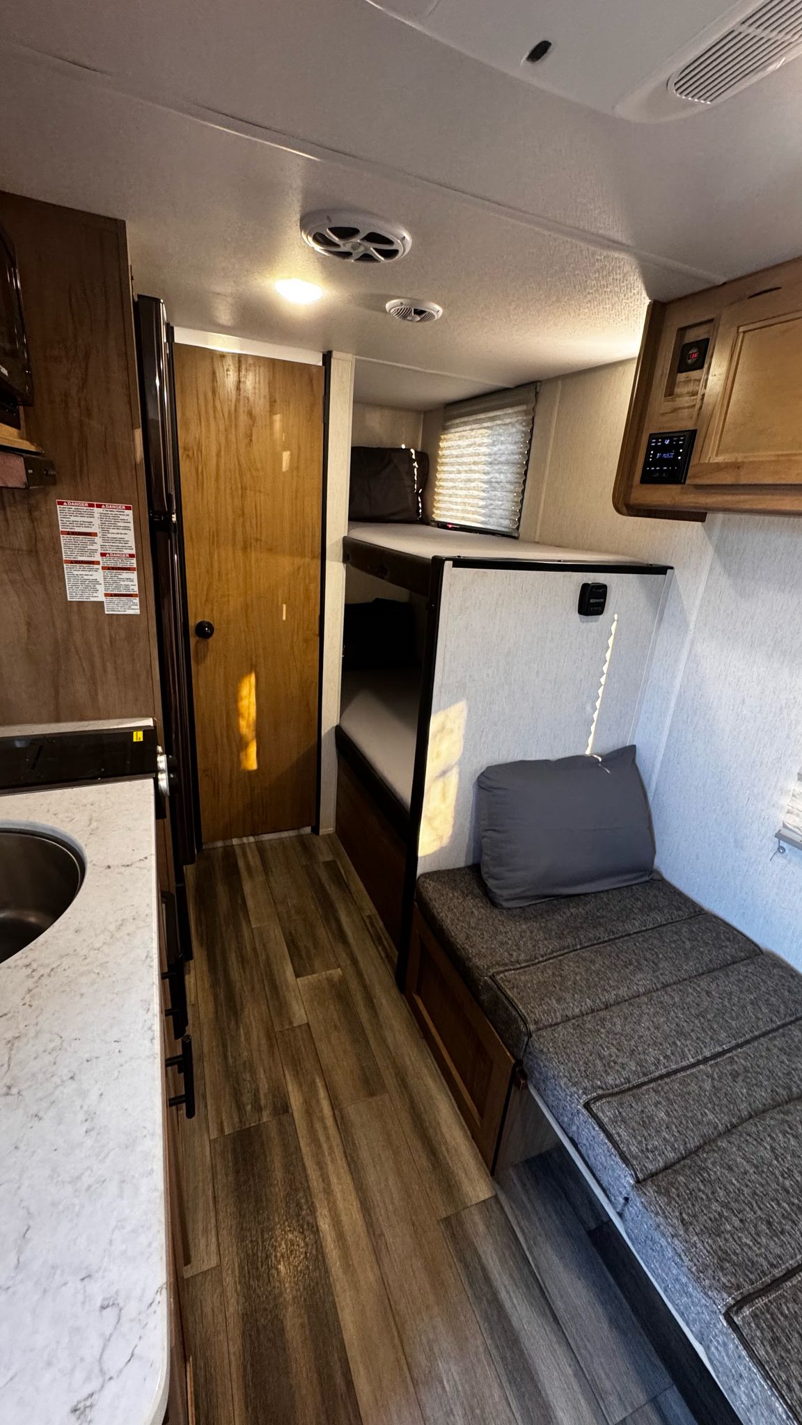 Step into this rv rental's interior: compact kitchen, wooden door, bunk beds, and bench seat. Natural light streams in.. Forest River Cherokee Wolf Pup 2023