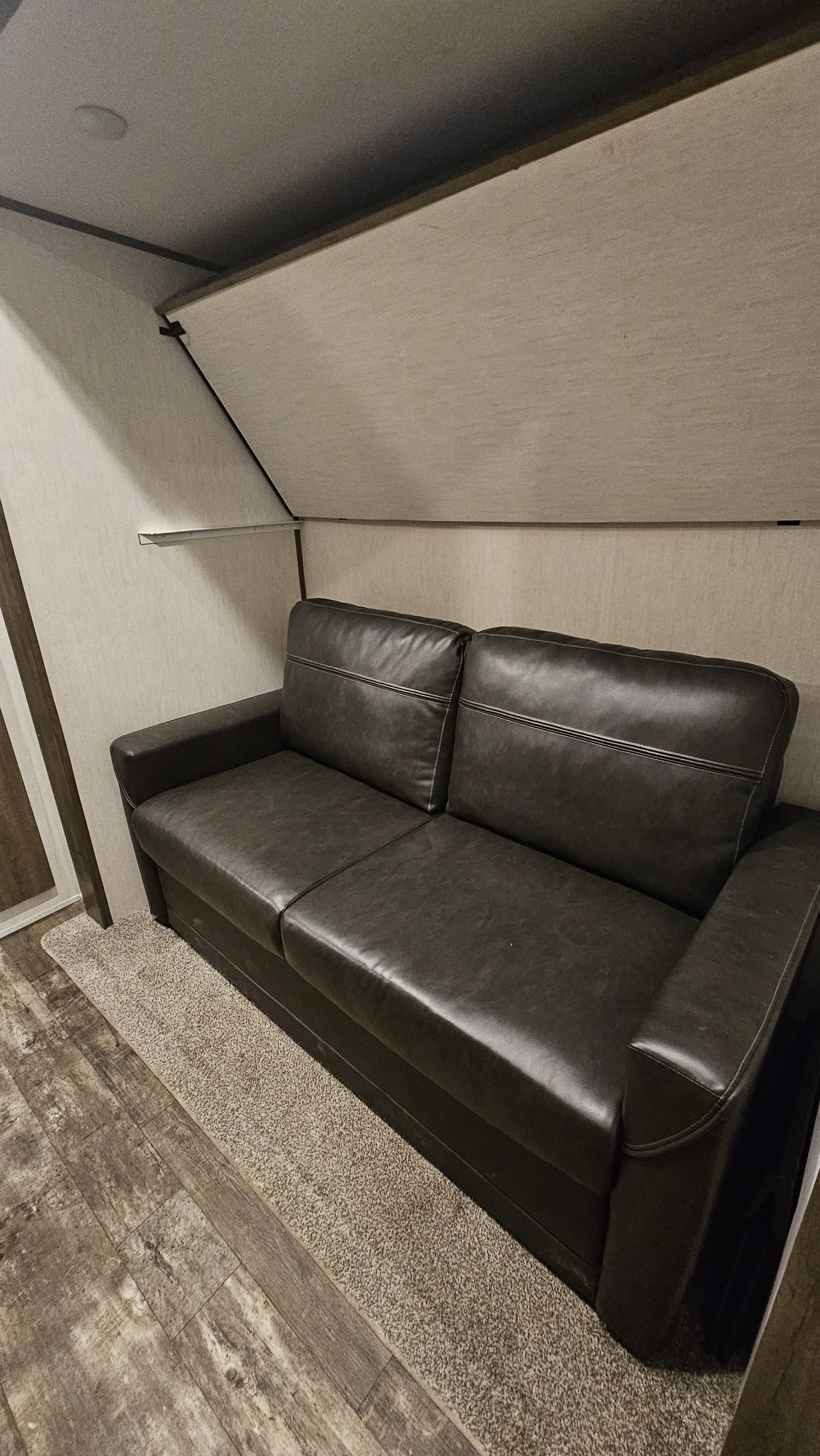 An RV rental interior features a dark leather sofa, likely a sleeper, with a fold-down bunk overhead.. Forest River Sabre 2022