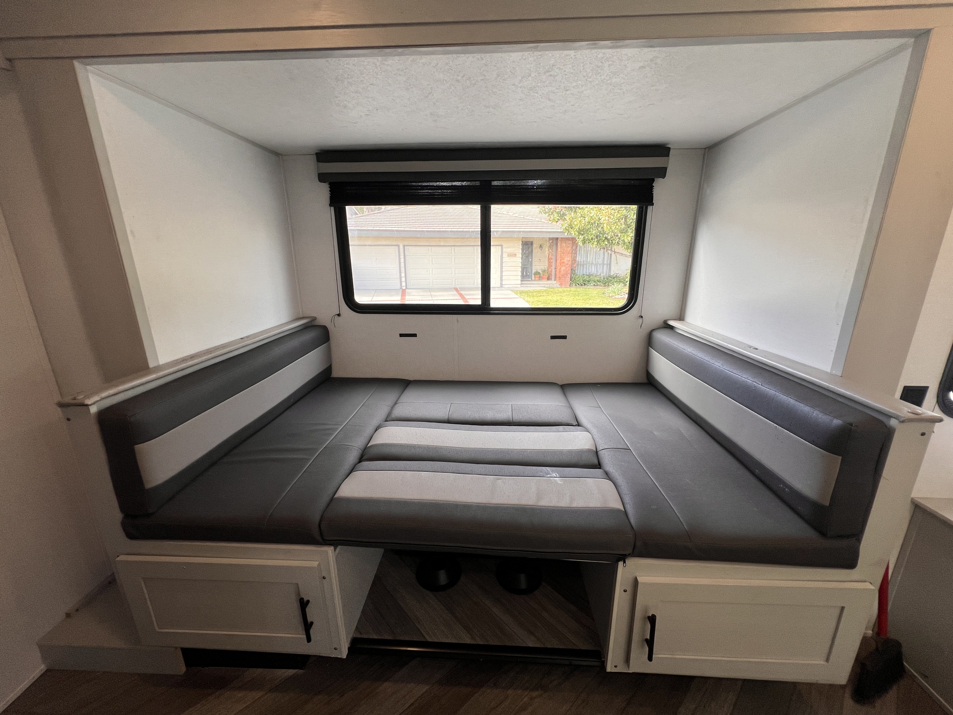 Bright RV rental interior showcasing a gray and light gray cushioned dinette that converts into a cozy bed.. Forest River Salem FSX 2021