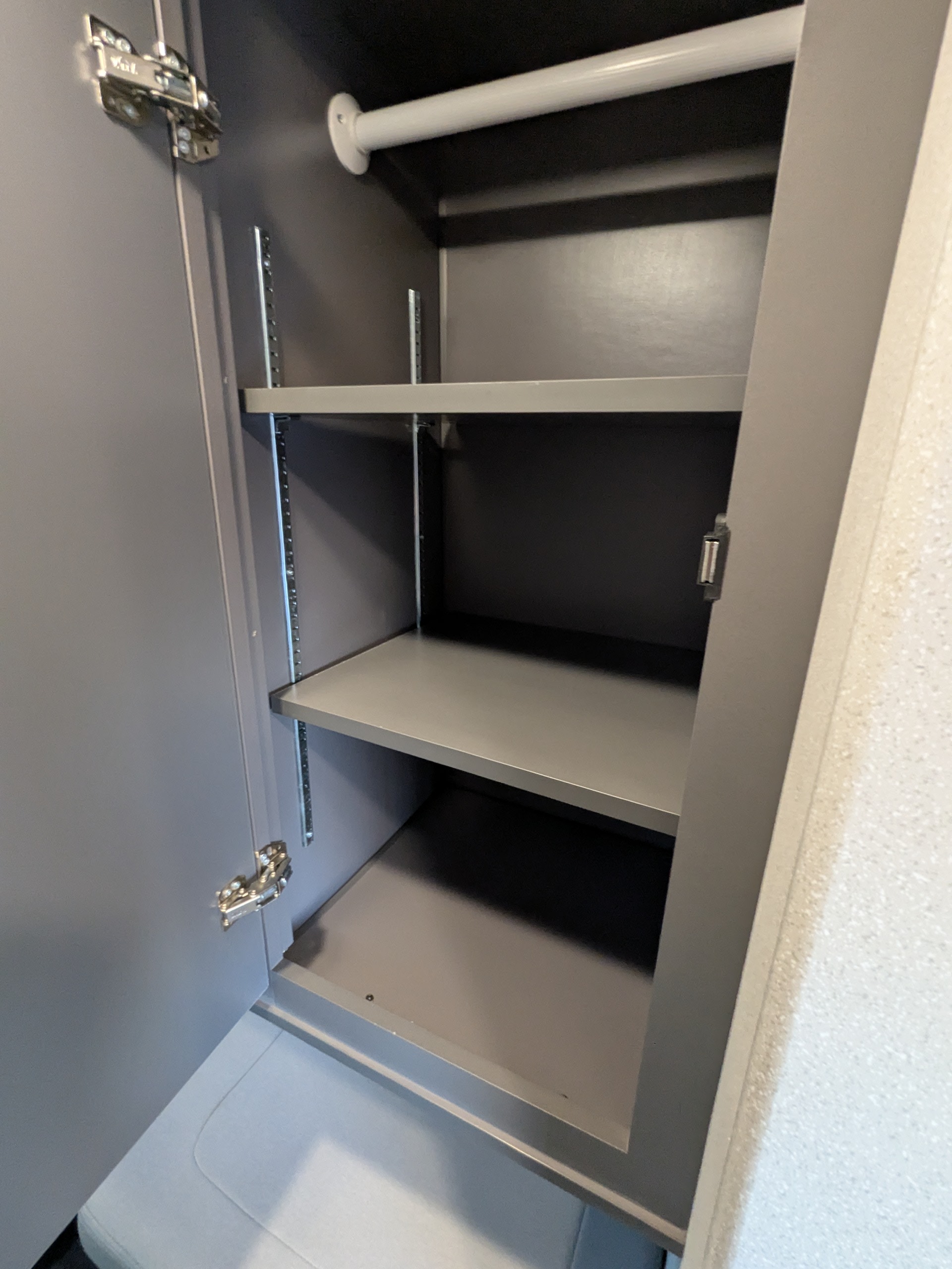 RV rental: View inside a small, grey cabinet with a white hanging rod, two adjustable shelves, and visible door hinges.. Thor Dazzle 2024