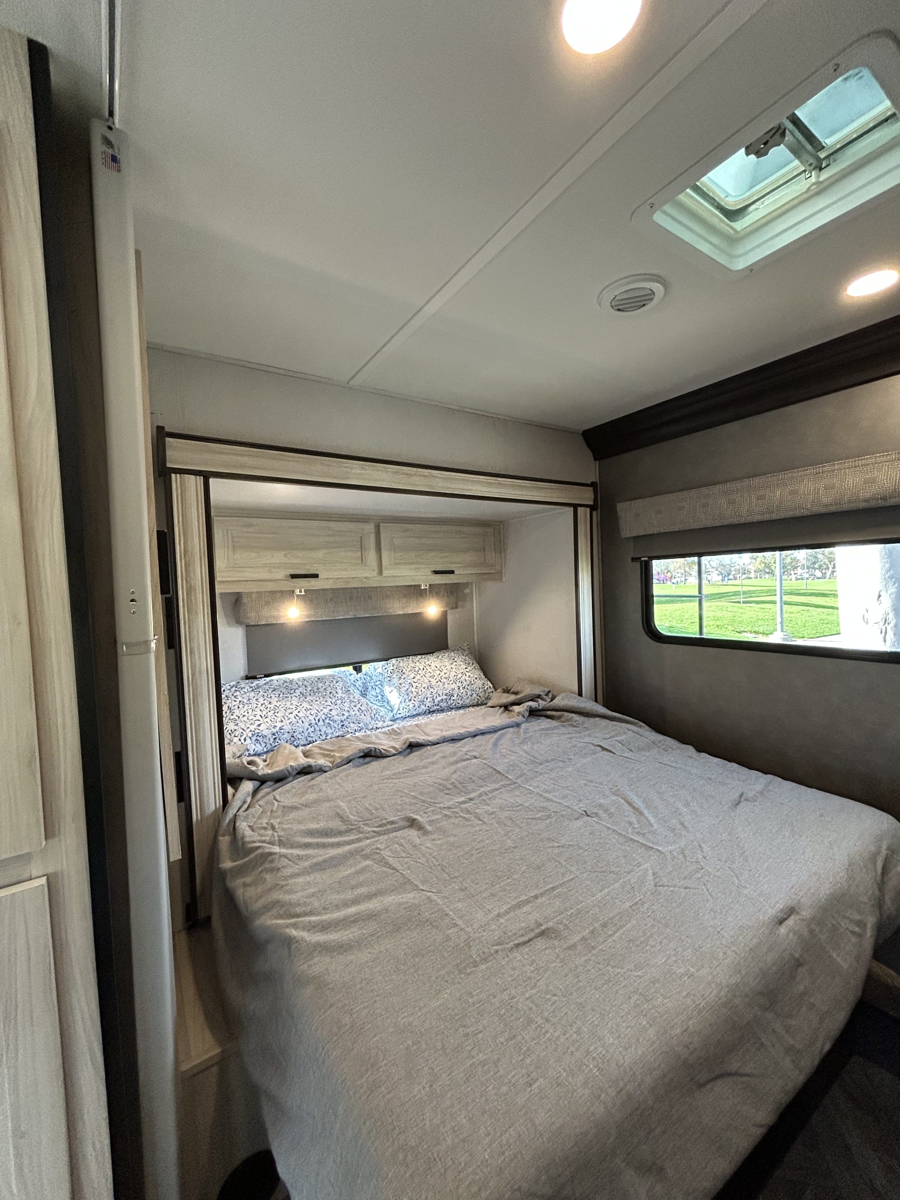 Spacious RV rental bedroom featuring a comfy bed, practical storage, and a scenic window view.. Forest River Sunseeker Classic 2023