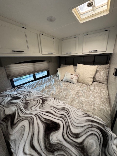 Inviting RV rental bedroom: cozy bed with marbled blanket, patterned bedding, white overhead cabinets, & skylight.. 1FDWE3FN5NDC05003 Coachman Crosstrail XL 23XG 2022