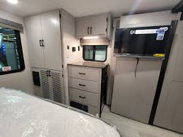 Spacious RV rental bedroom with modern light wood cabinetry, dresser, wardrobe, and mounted TV. Great for travel.. Couchmen Entourage 340BH 2025