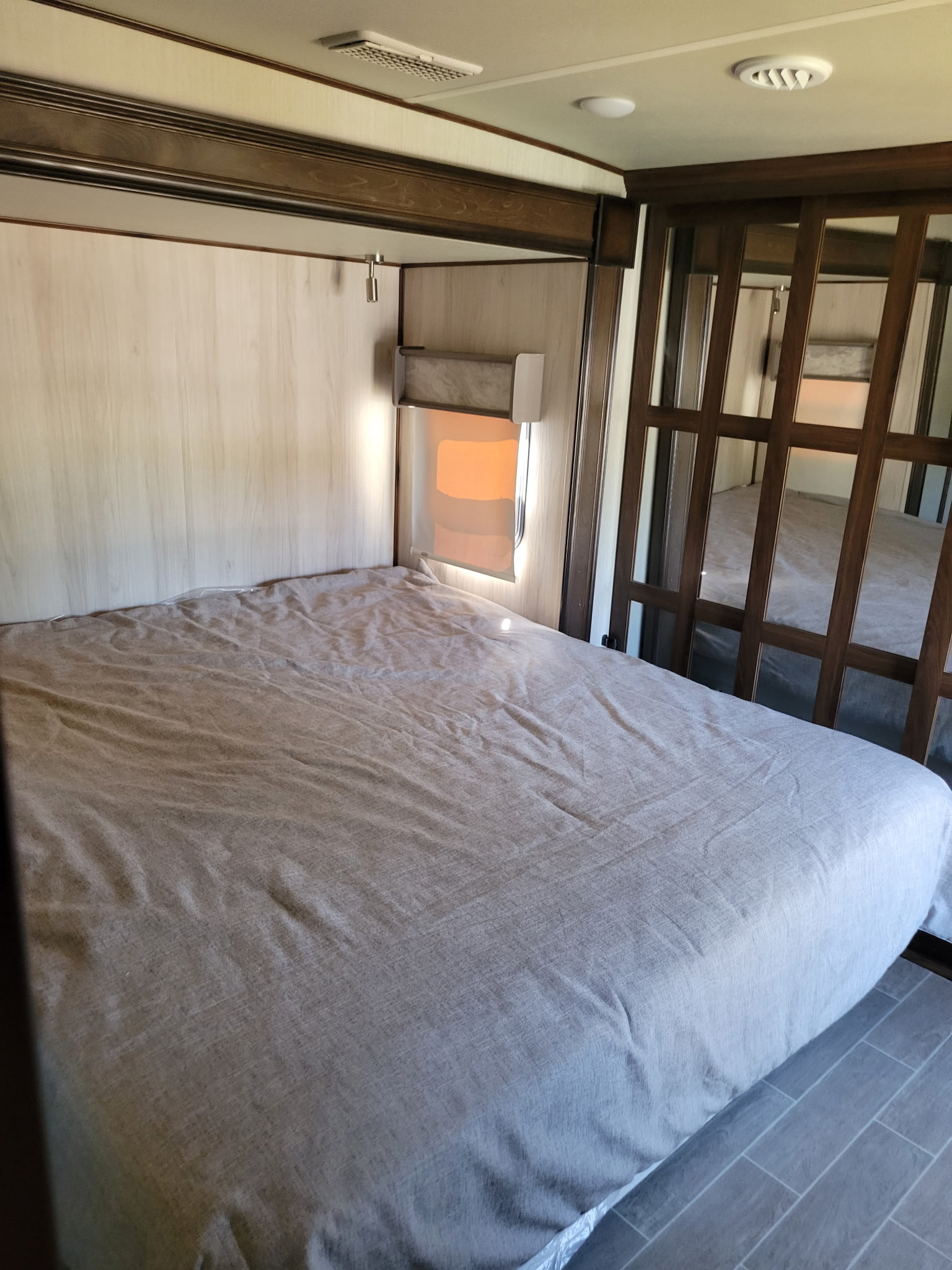 RV rental bedroom with queen bed, modern wood paneling, and mirrored closet. Bright and comfortable.. Palomino Puma 2020