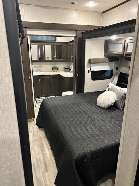 Modern RV rental interior featuring a spacious bedroom with a black bed and an attached bathroom.. Coachman Brookstone 344 FL 2021