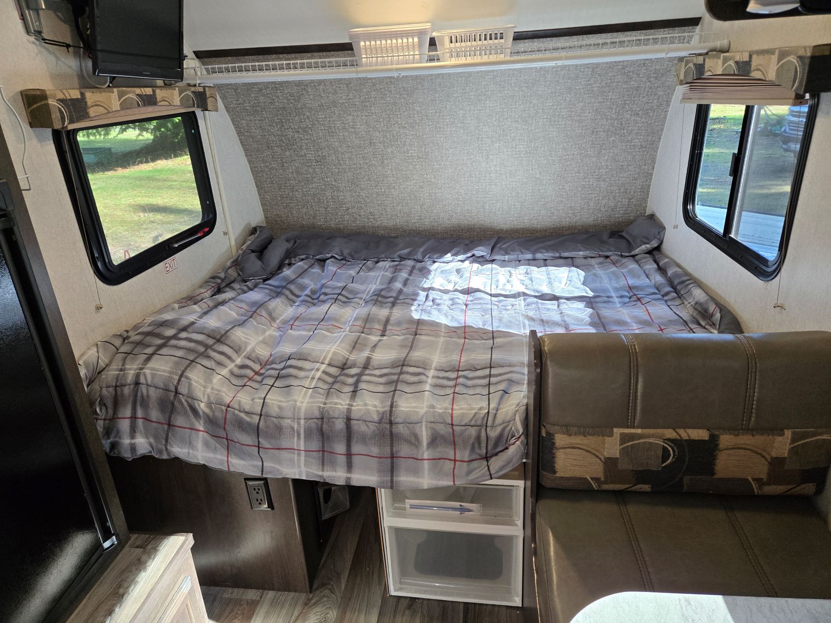 Inside an rv rental: a cozy bedroom with plaid bedding, two windows, TV, and built-in dinette seating. Perfect for travel.. Starcraft Satellite 2019