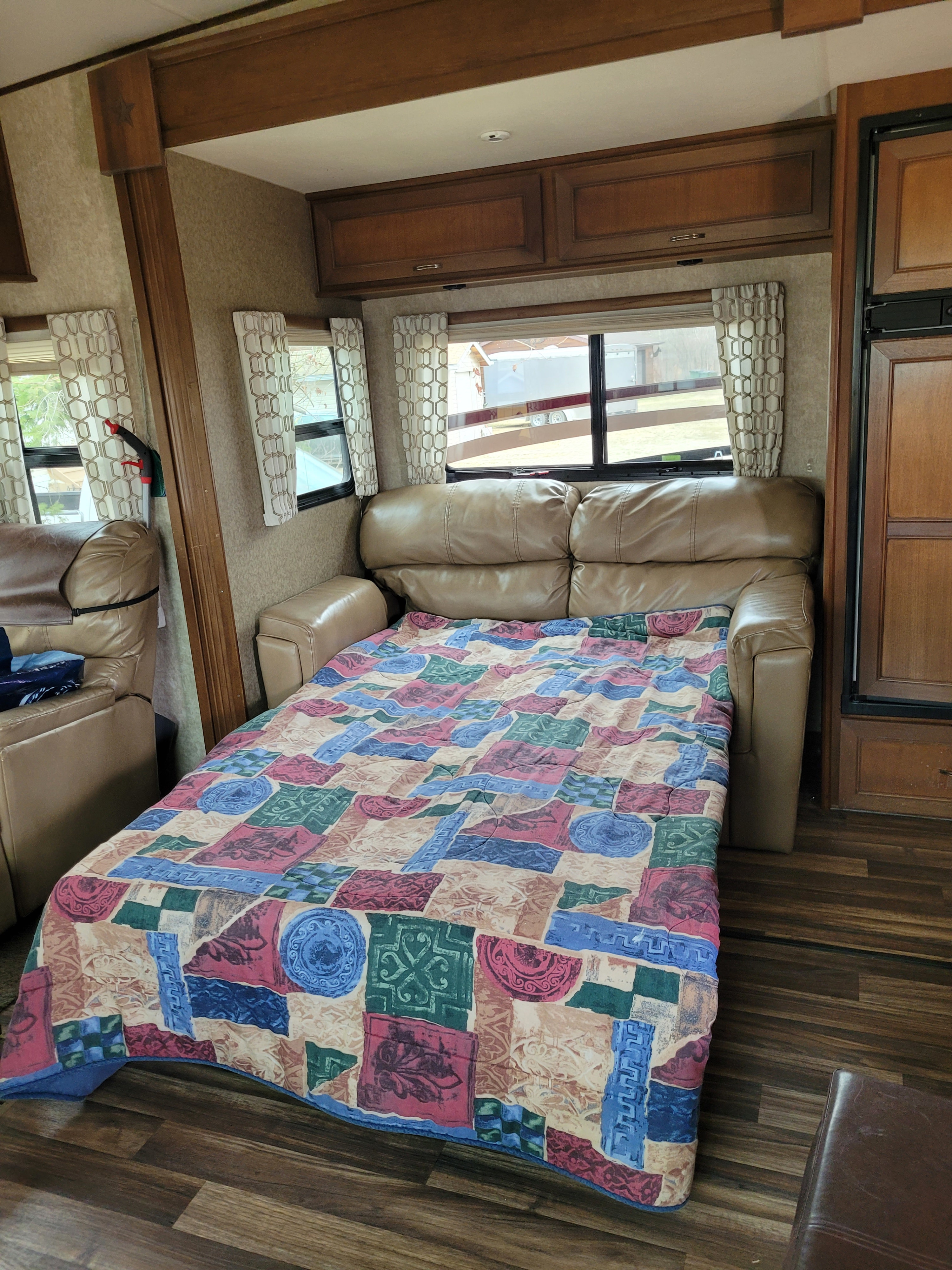RV rental interior featuring a pull-out leather sofa bed with a colorful quilt for comfortable sleeping.. Open Range RV Open Range RV Fifth Wheel 2015