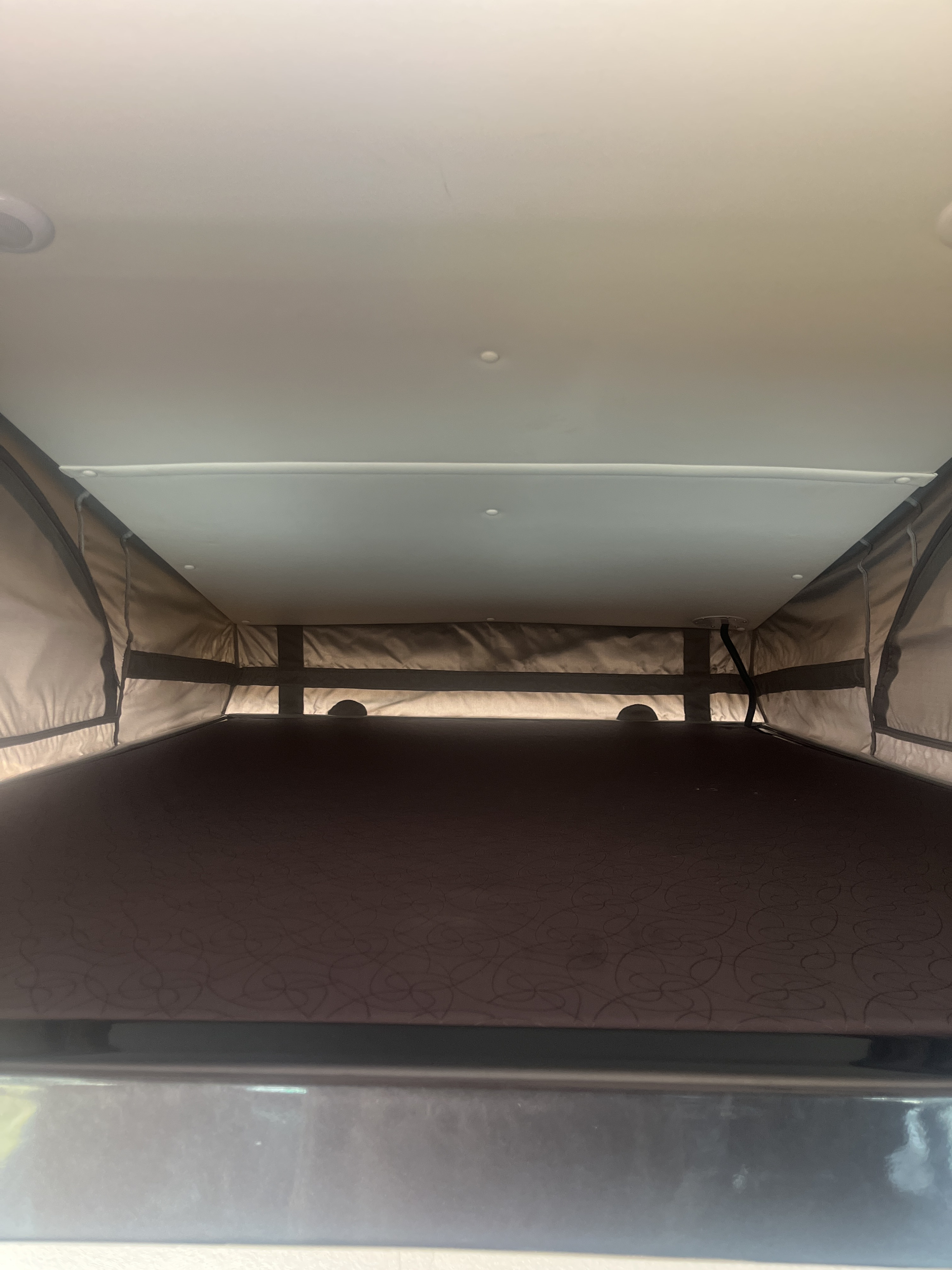 Inside an RV rental pop-top camper: a view of the elevated sleeping area with its bed, fabric walls, and ceiling.. Pleasure-Way Pleasure-Way Class B 2022