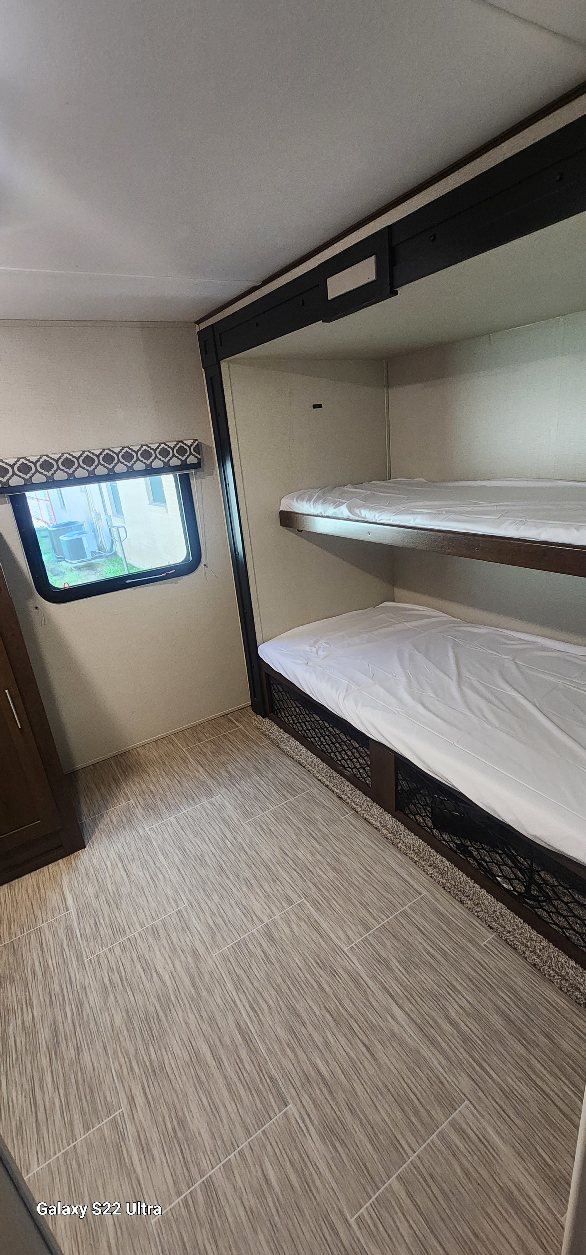 RV rental bunk bed interior with white sheets, window view, and lower storage. Perfect for family adventures.. Forest River Tracer Breeze 2019
