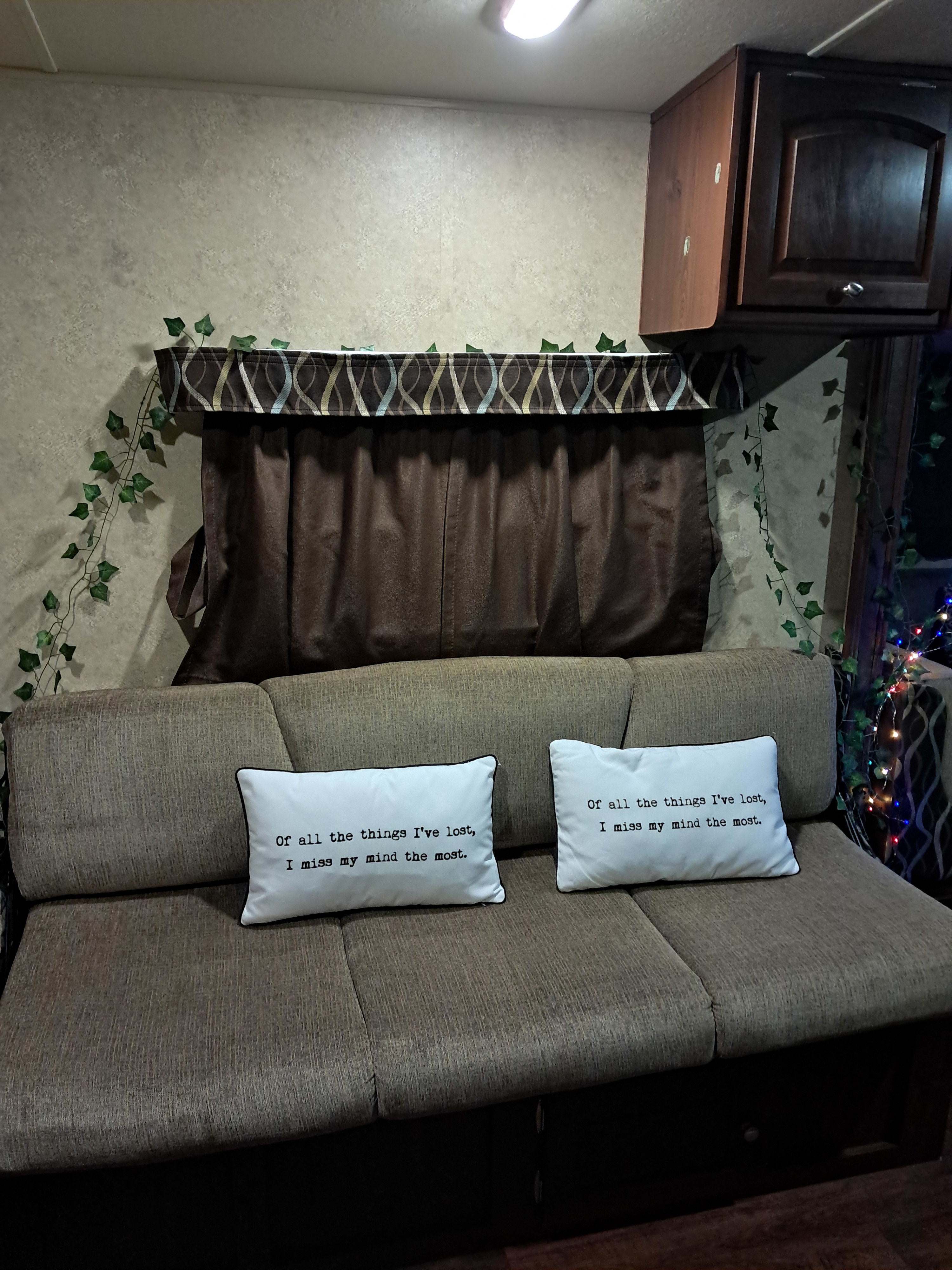 Enjoying a cozy RV rental interior, featuring a sofa with humorous "lost mind" pillows and decorative ivy vines.. Forest River Flagstaff Shamrock 2014