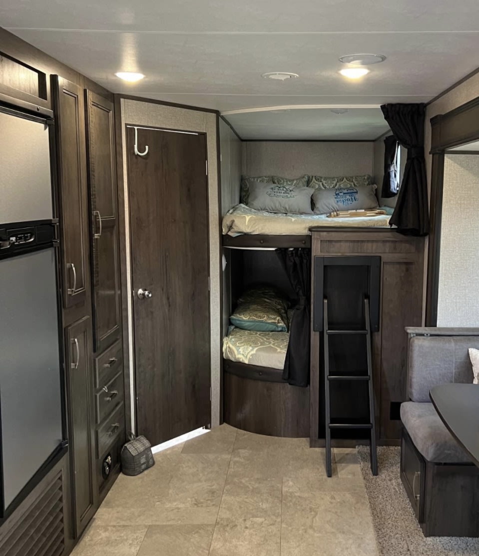 Spacious RV rental interior: view of bunk beds, functional kitchen area, and dinette. Ideal for comfortable camper travel.. Jayco Jay Flight SLX 2021