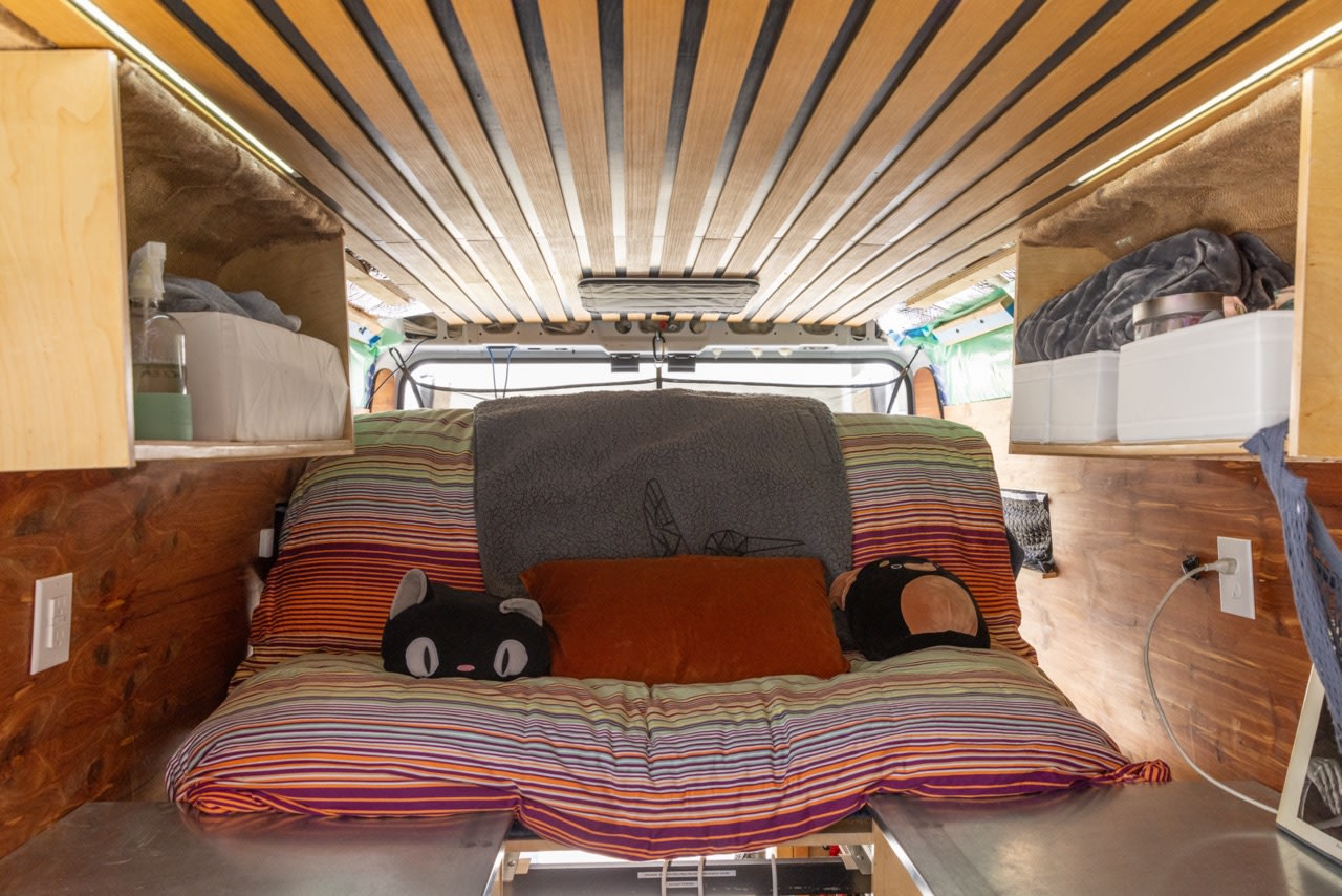 Cozy view inside an rv rental camper van: striped bed, slatted wood ceiling, and organized overhead storage.. Dodge Ram Promaster Cargo Van 2500 159" WB 2018