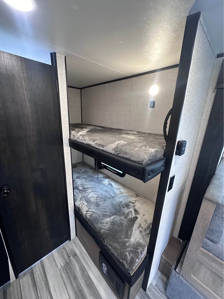 Cozy RV rental interior with two stacked bunk beds, featuring soft grey blankets and individual lighting, perfect for families.. Jayco Jay Flight SLX 2024