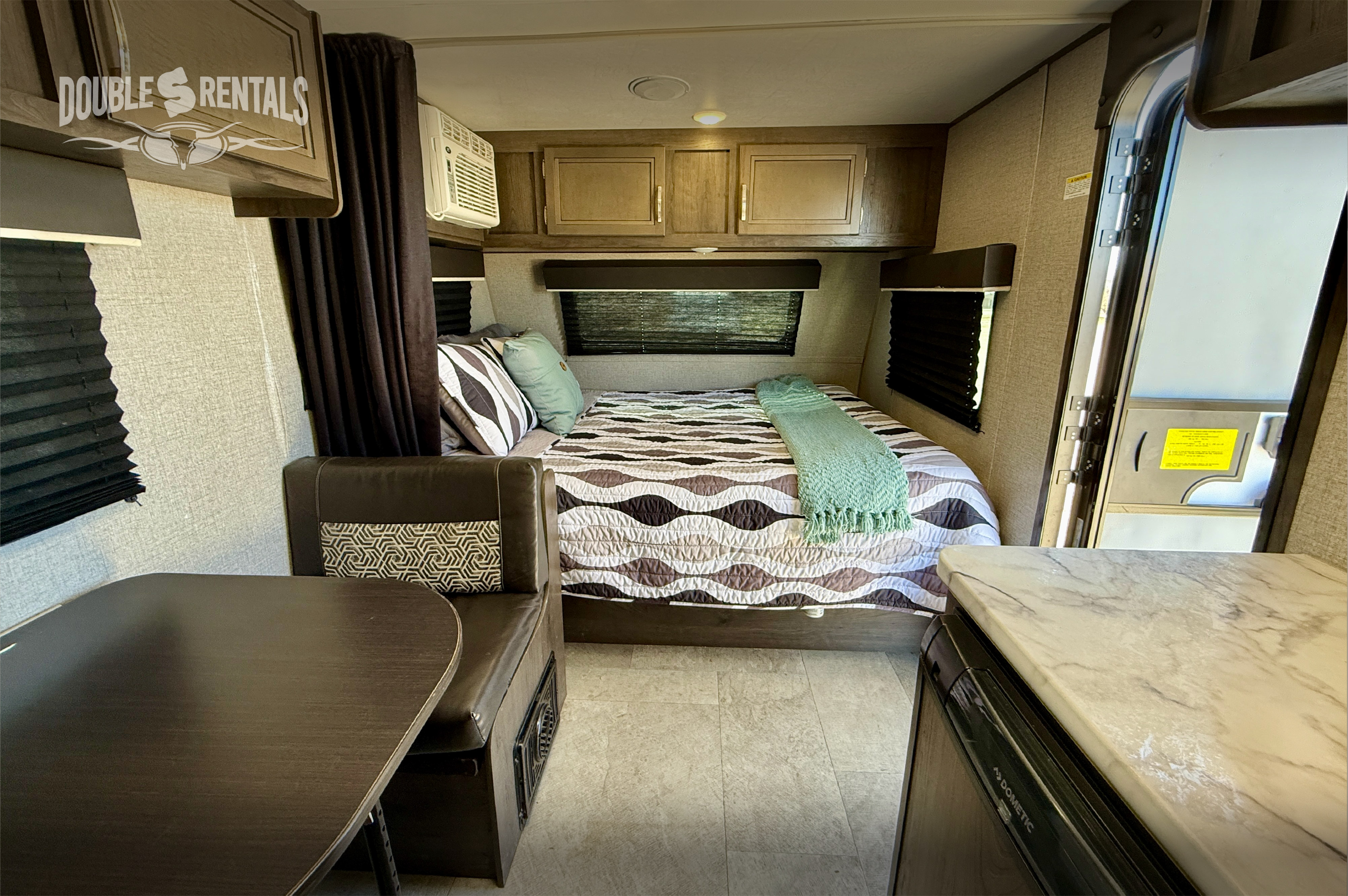 Spacious RV rental interior: comfortable bed, dining booth, overhead cabinets, and a compact kitchen counter for your travels.. Jayco Jay Flight 174BH 2020