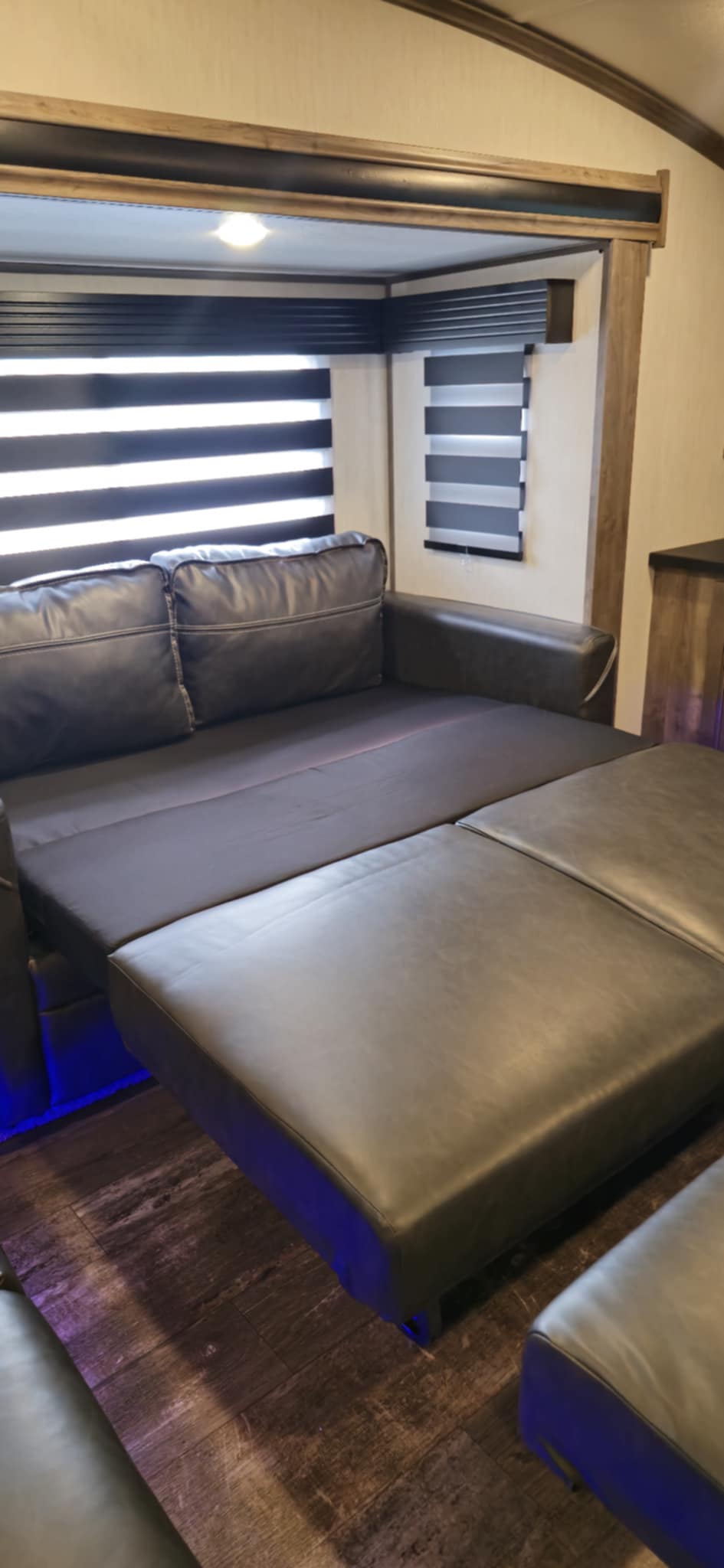 Modern RV rental interior with a versatile sofa that converts into a bed, featuring stylish zebra blinds and accent lighting.. Forest River Sabre 2022