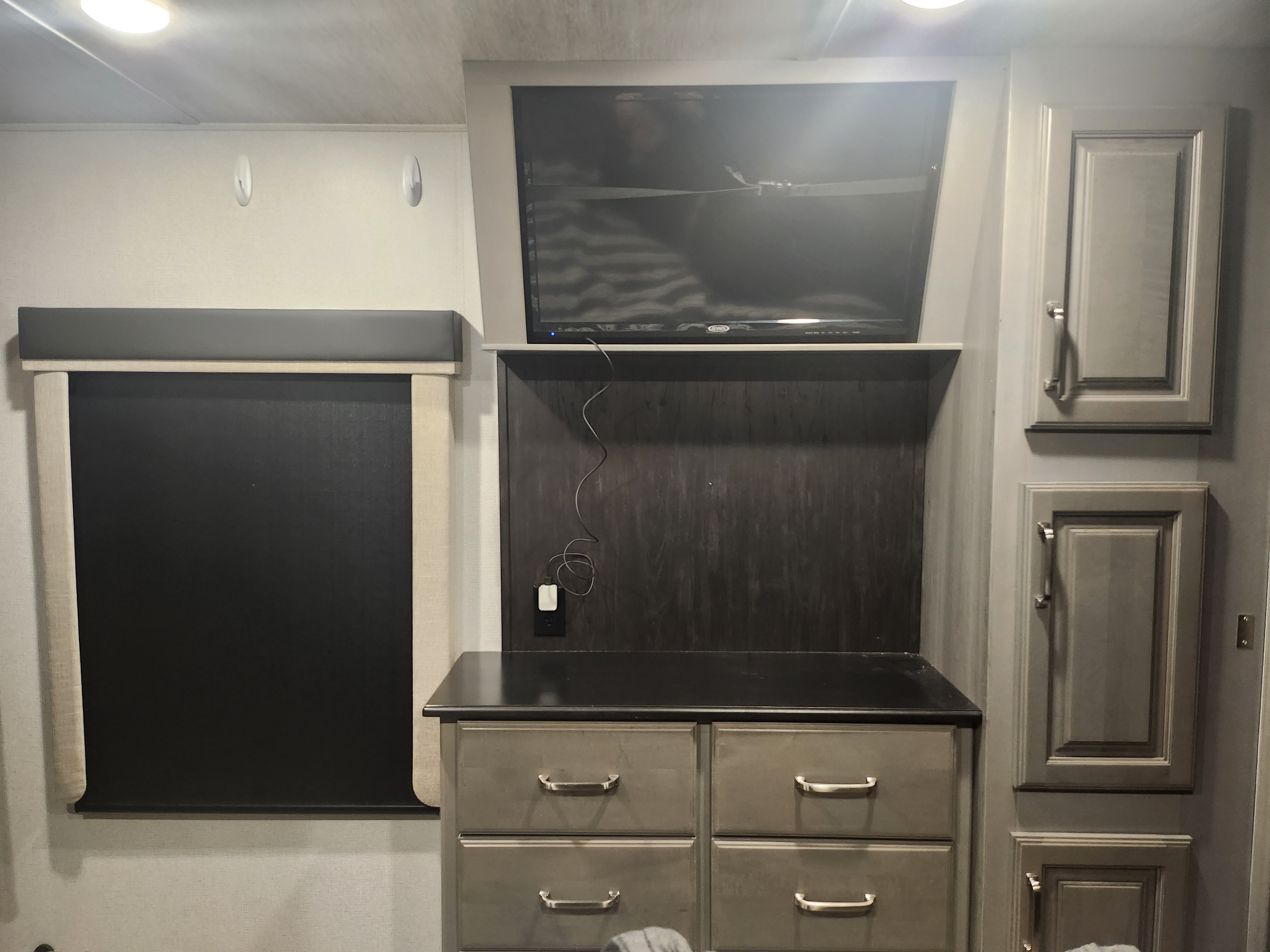 Modern RV rental bedroom: Features a mounted TV, ample storage, and blackout shades for cozy travel nights.. Keystone RV Montana 2021