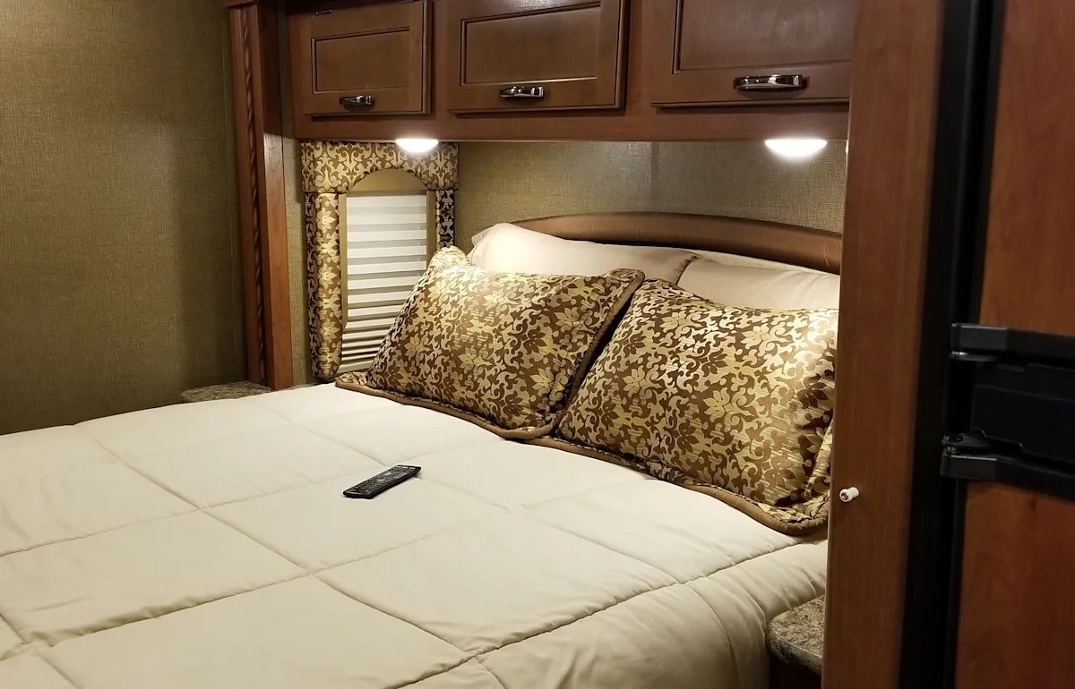 Comfortable RV rental bedroom with a queen bed, overhead cabinets, and stylish decor for your next adventure.. Thor Motor Coach Freedom Elite 29FE 2017