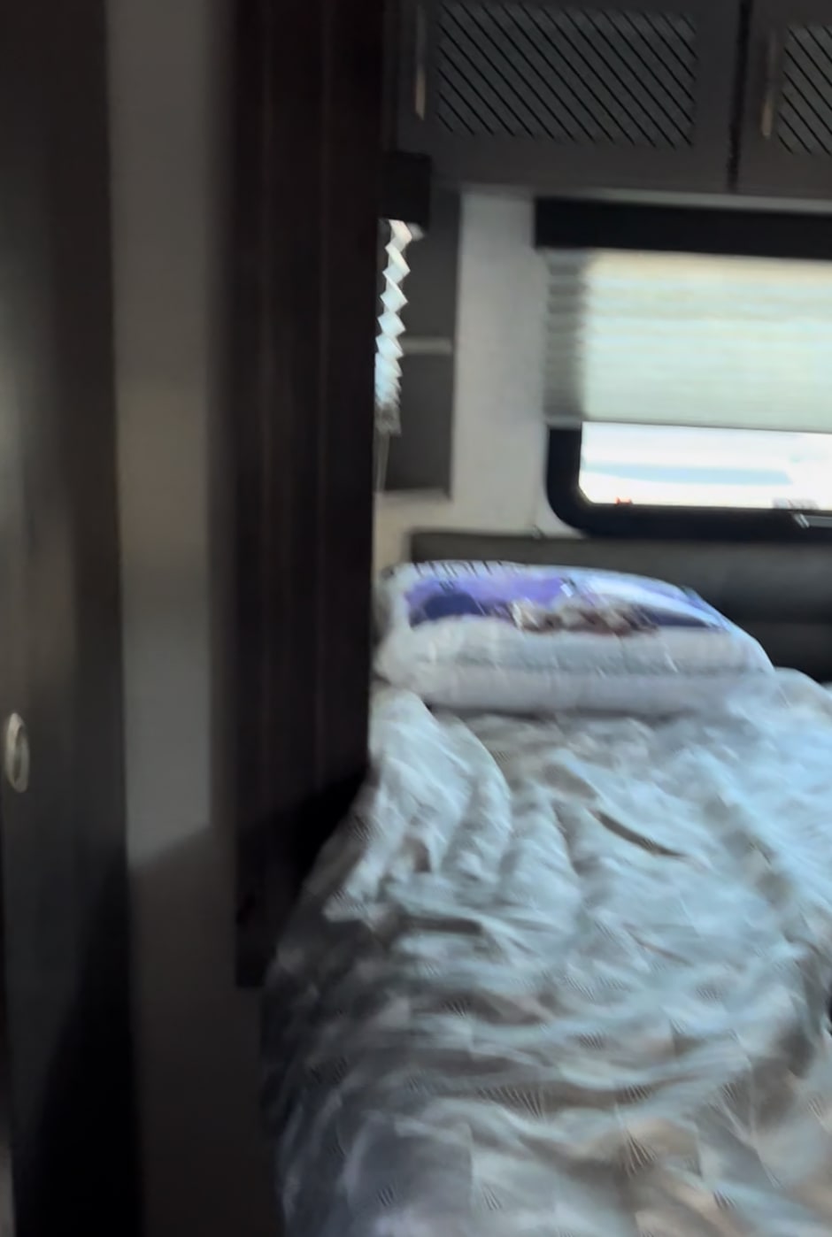 Comfortable RV rental bedroom with patterned bedding, window, and cabinets. Ideal for your next trip.. Grand Design Momentum Toy Hauler 2022